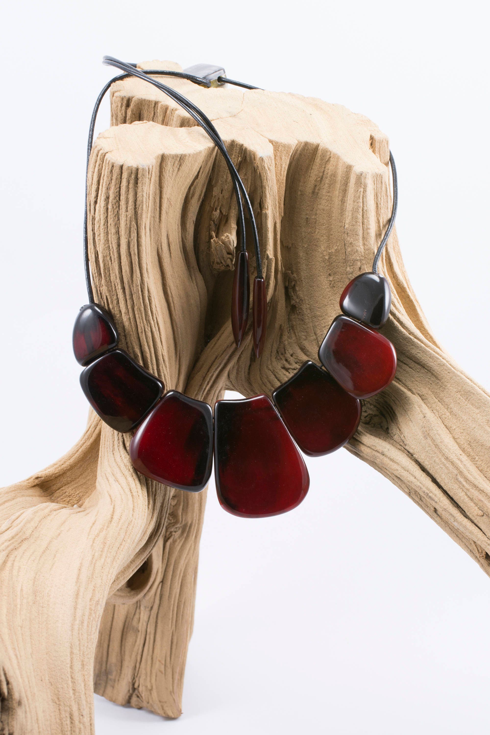 A vibrant statement red necklace made of natural horn, featuring smooth volumetric ovals and a leather cord with teardrop ends.