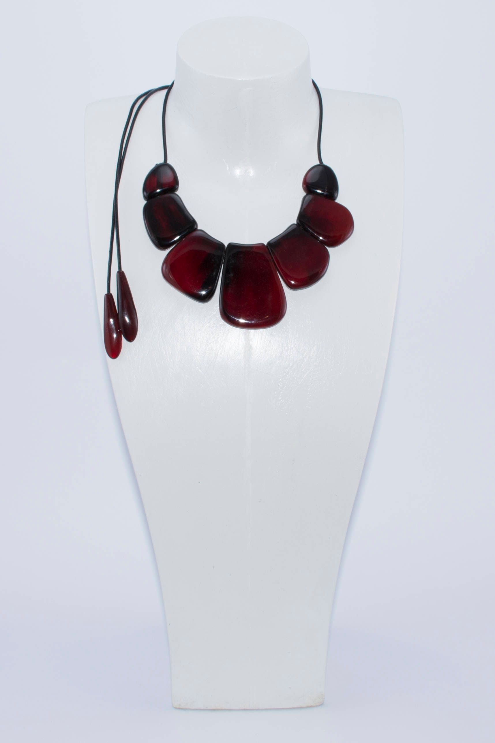 A vibrant statement red necklace made of natural horn, featuring smooth volumetric ovals and a leather cord with teardrop ends.