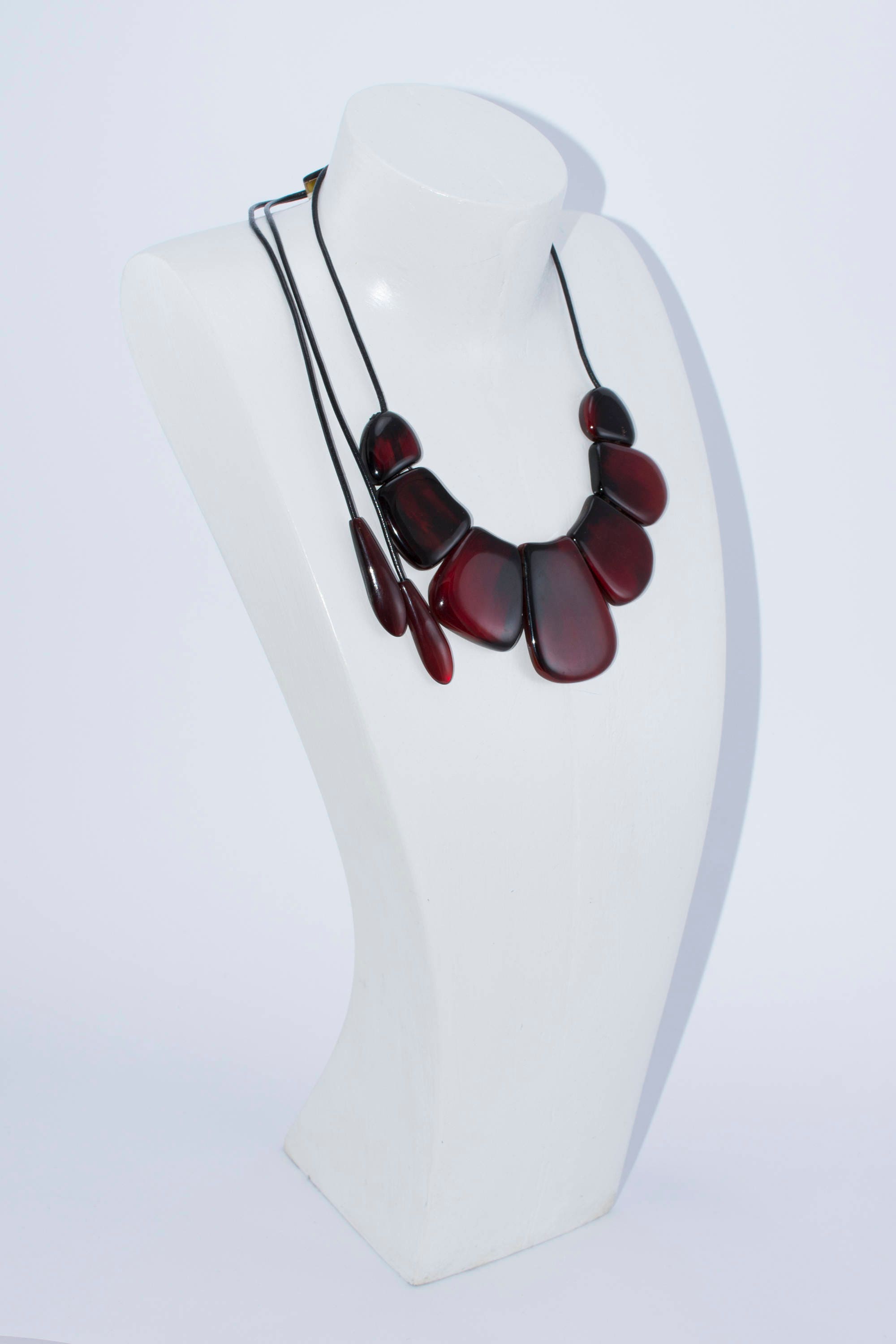 A vibrant statement red necklace made of natural horn, featuring smooth volumetric ovals and a leather cord with teardrop ends.