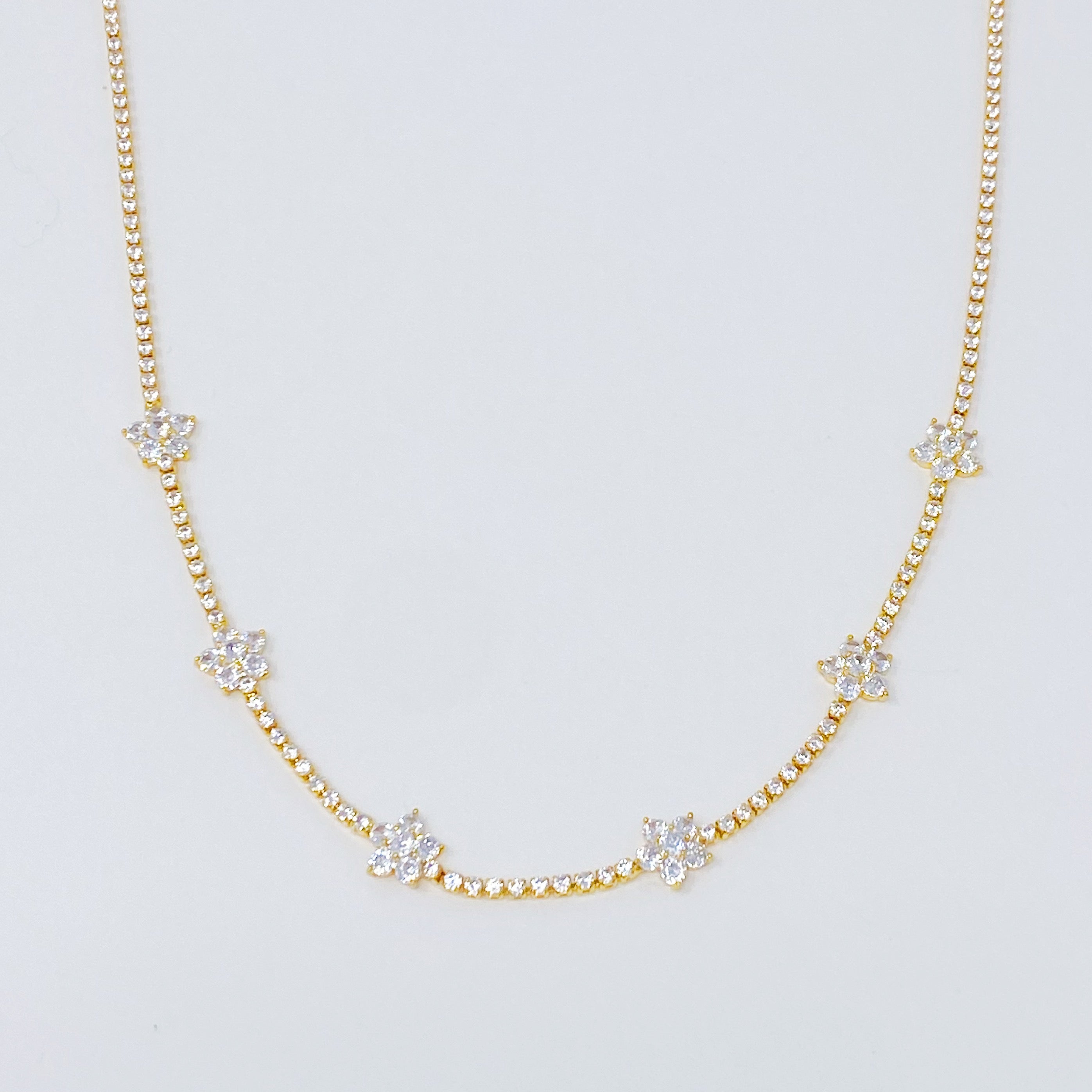 Stella Shiny Flower Necklace featuring clear stone flowers on a gold plated brass chain, adjustable length for versatile wear.