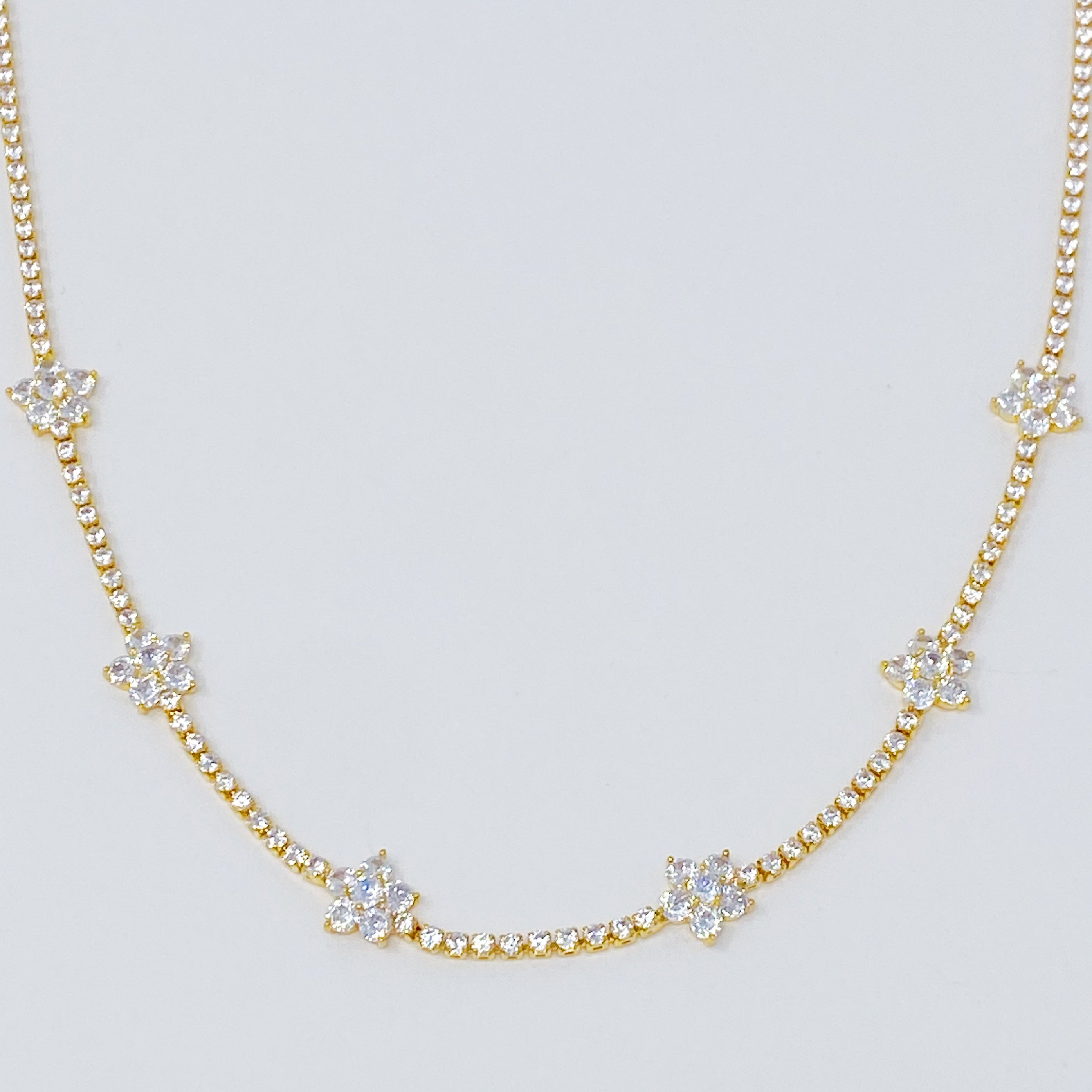 Stella Shiny Flower Necklace featuring clear stone flowers on a gold plated brass chain, adjustable length for versatile wear.