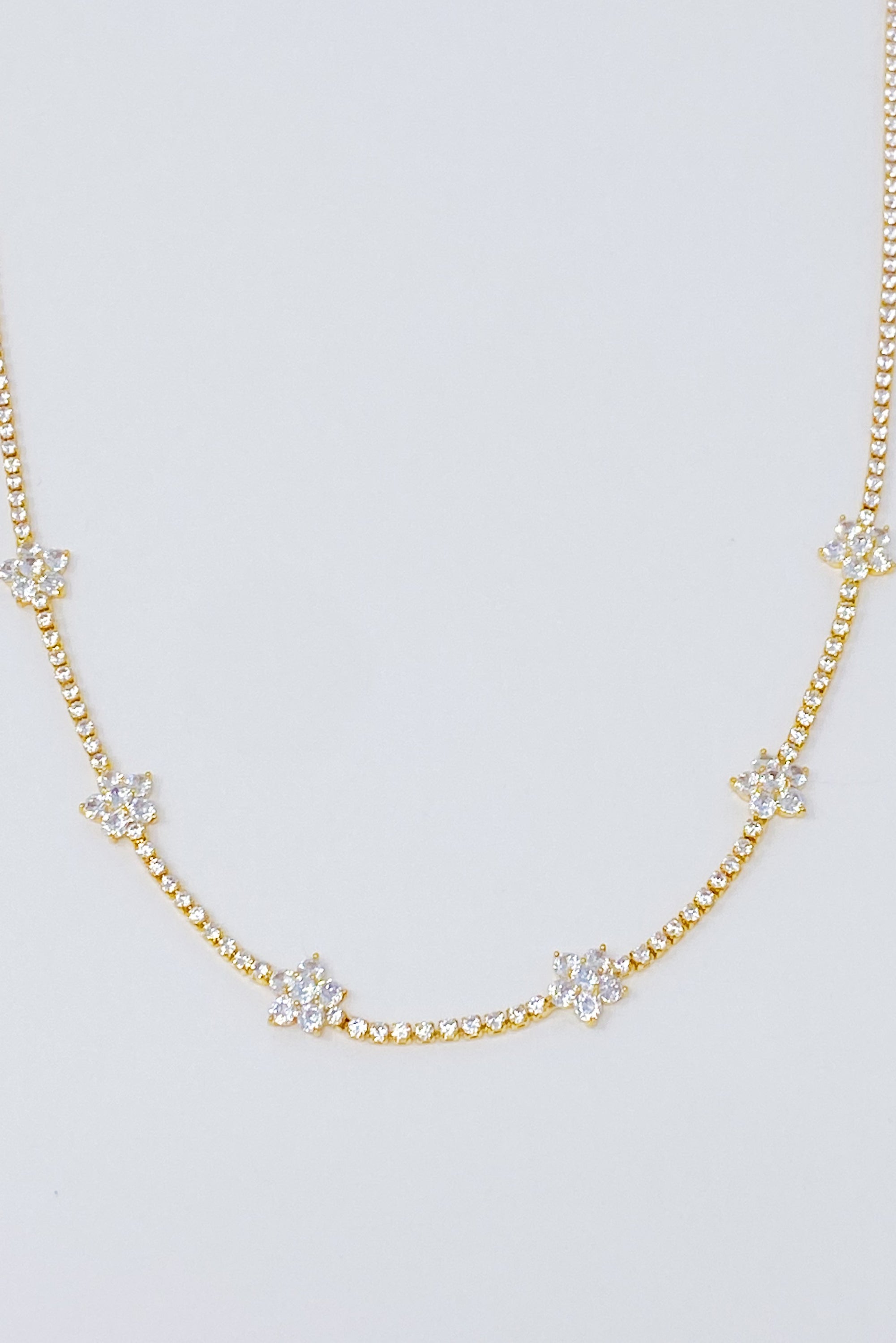 Stella Shiny Flower Necklace featuring clear stone flowers on a gold plated brass chain, adjustable length for versatile wear.