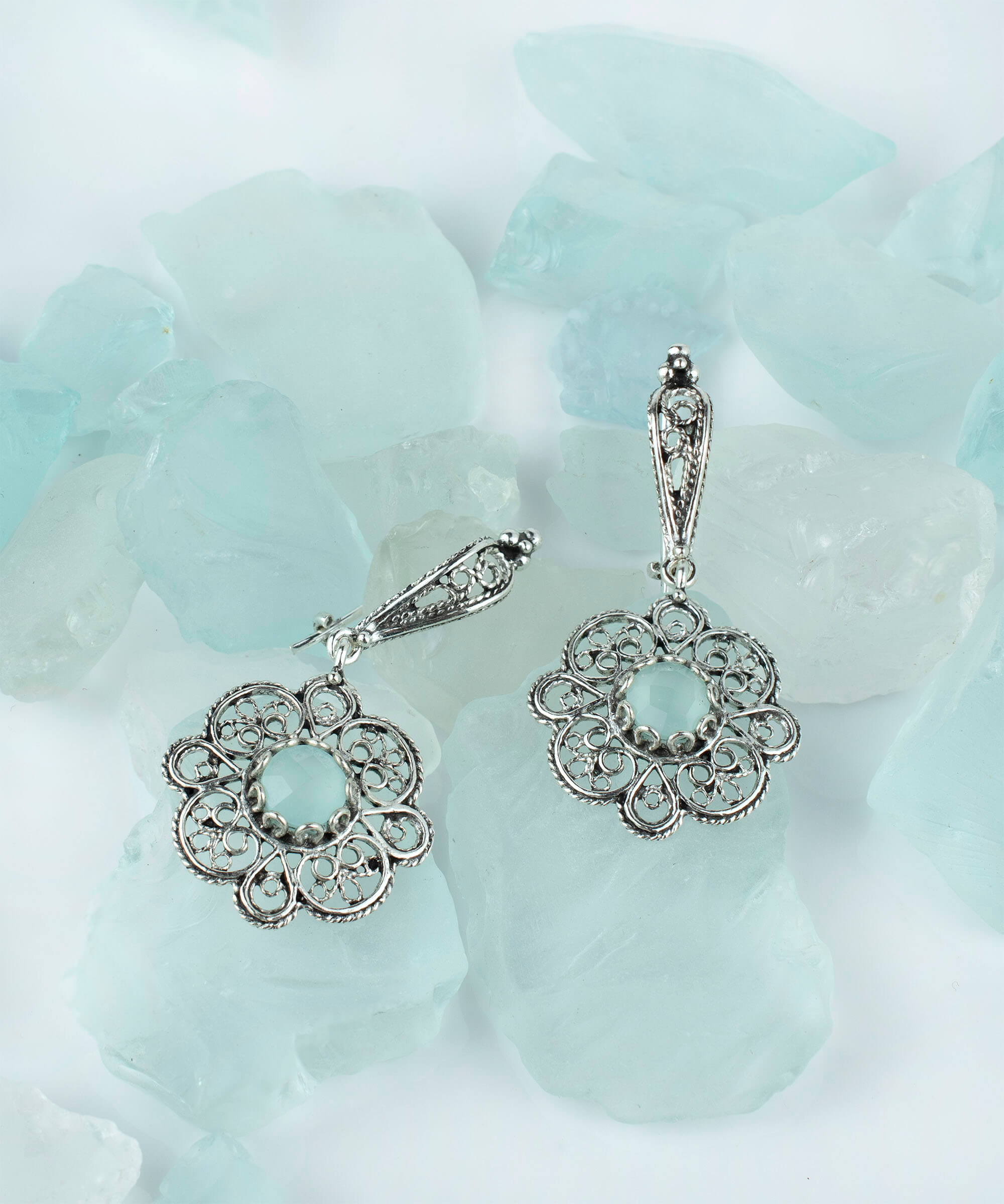 Handmade sterling silver dangle earrings featuring intricate filigree art and aqua blue chalcedony gemstone.