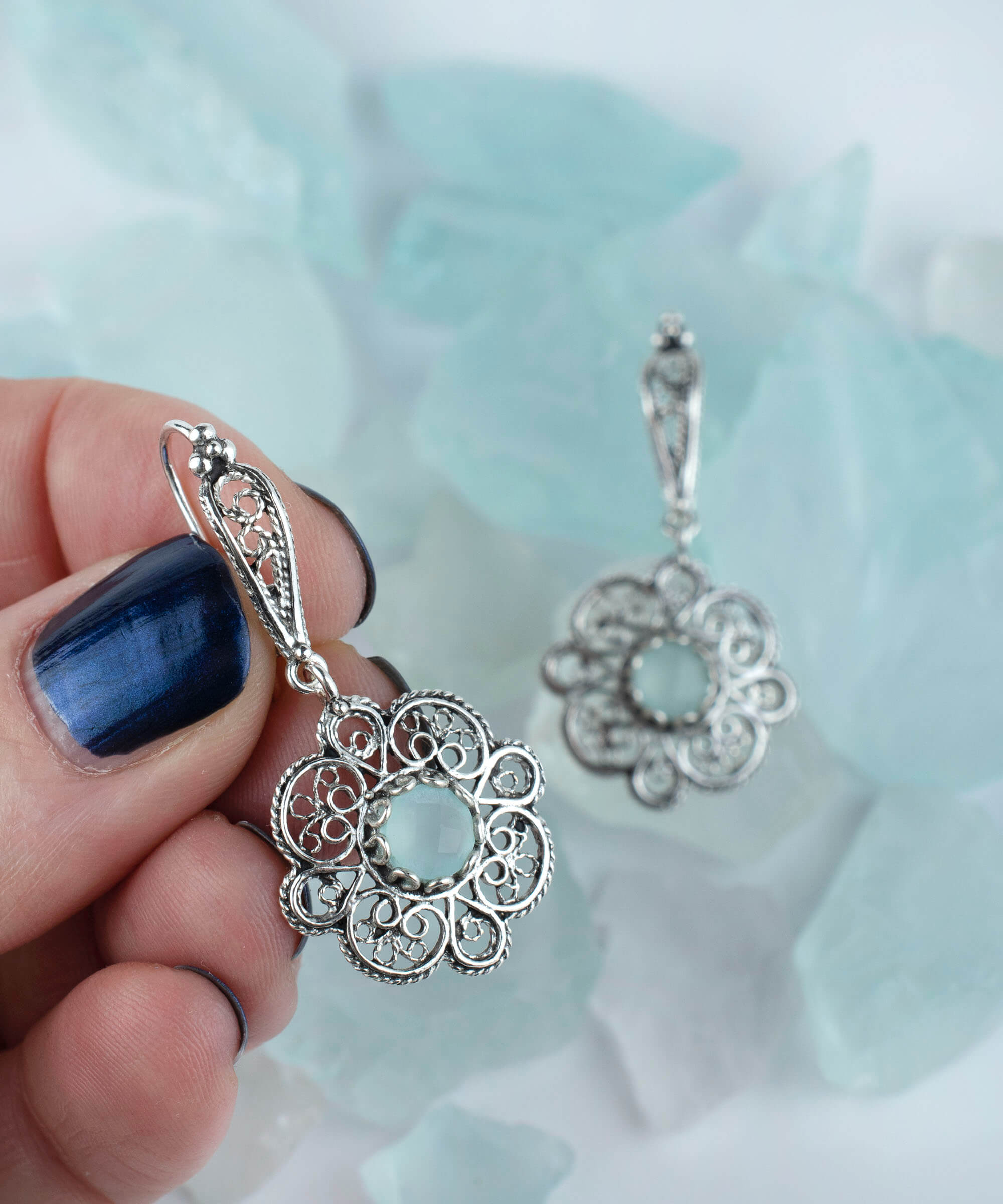 Handmade sterling silver dangle earrings featuring intricate filigree art and aqua blue chalcedony gemstone.