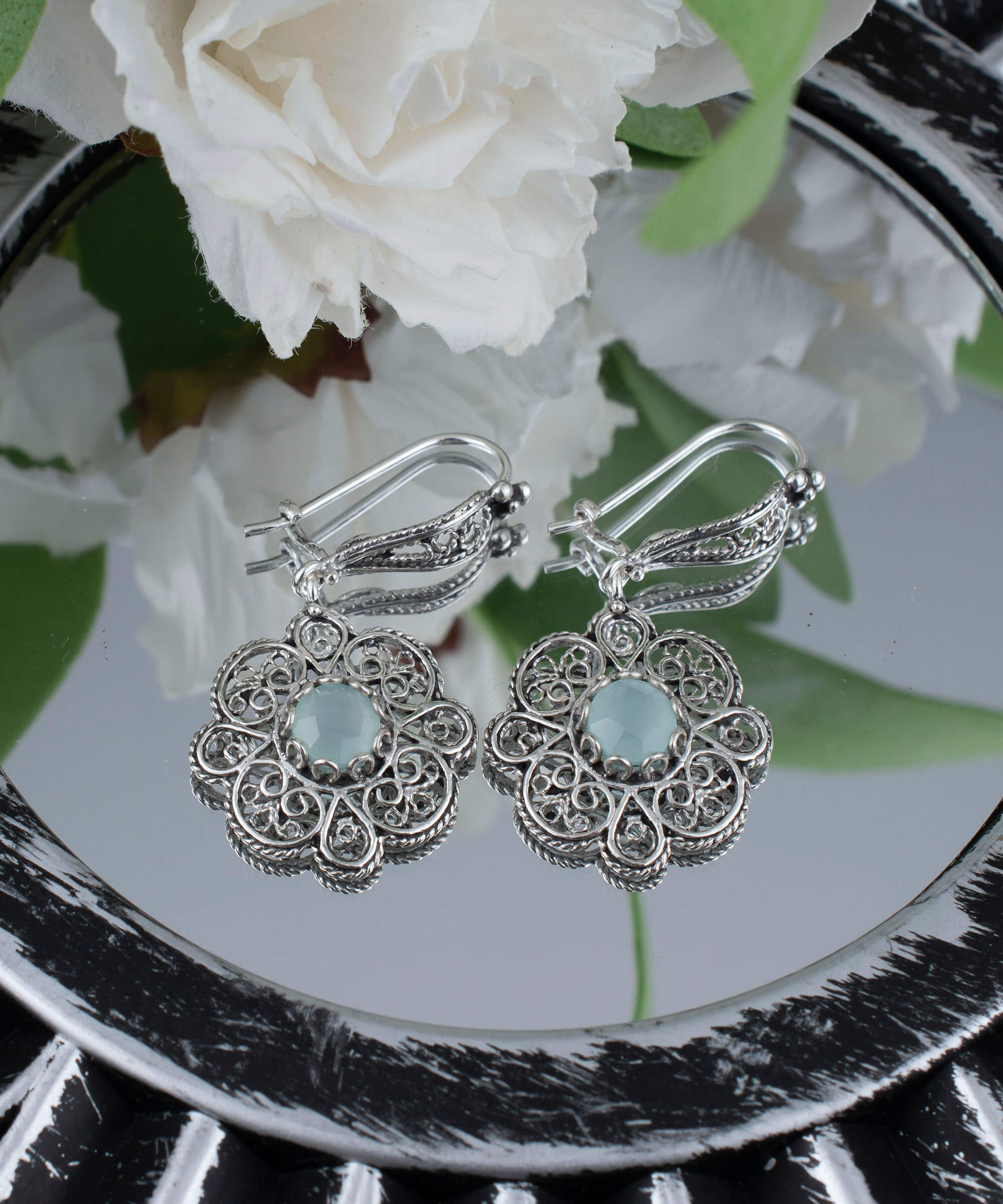 Handmade sterling silver dangle earrings featuring intricate filigree art and aqua blue chalcedony gemstone.