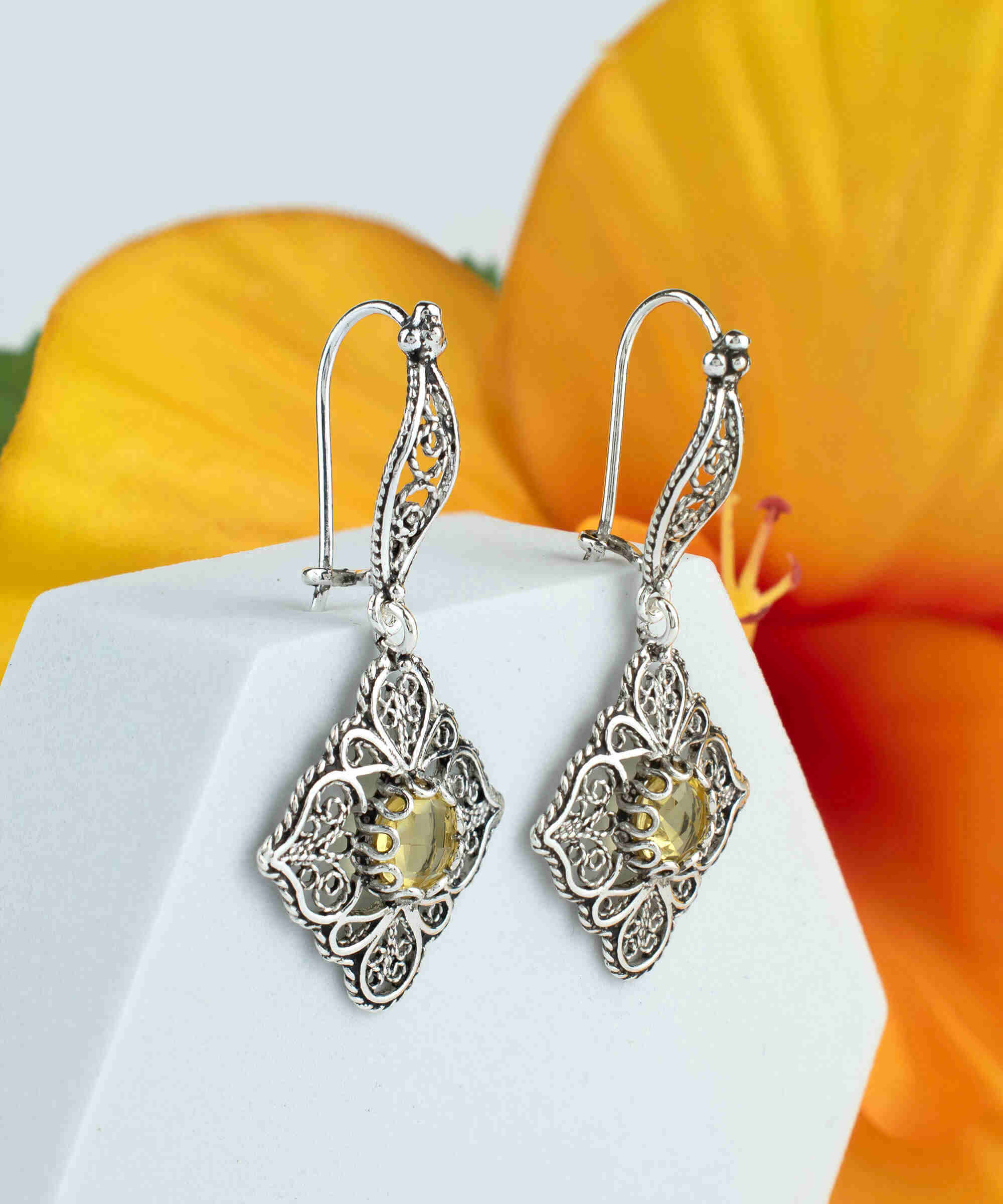 Elegant sterling silver dangle earrings featuring intricate filigree art and vibrant citrine gemstones.