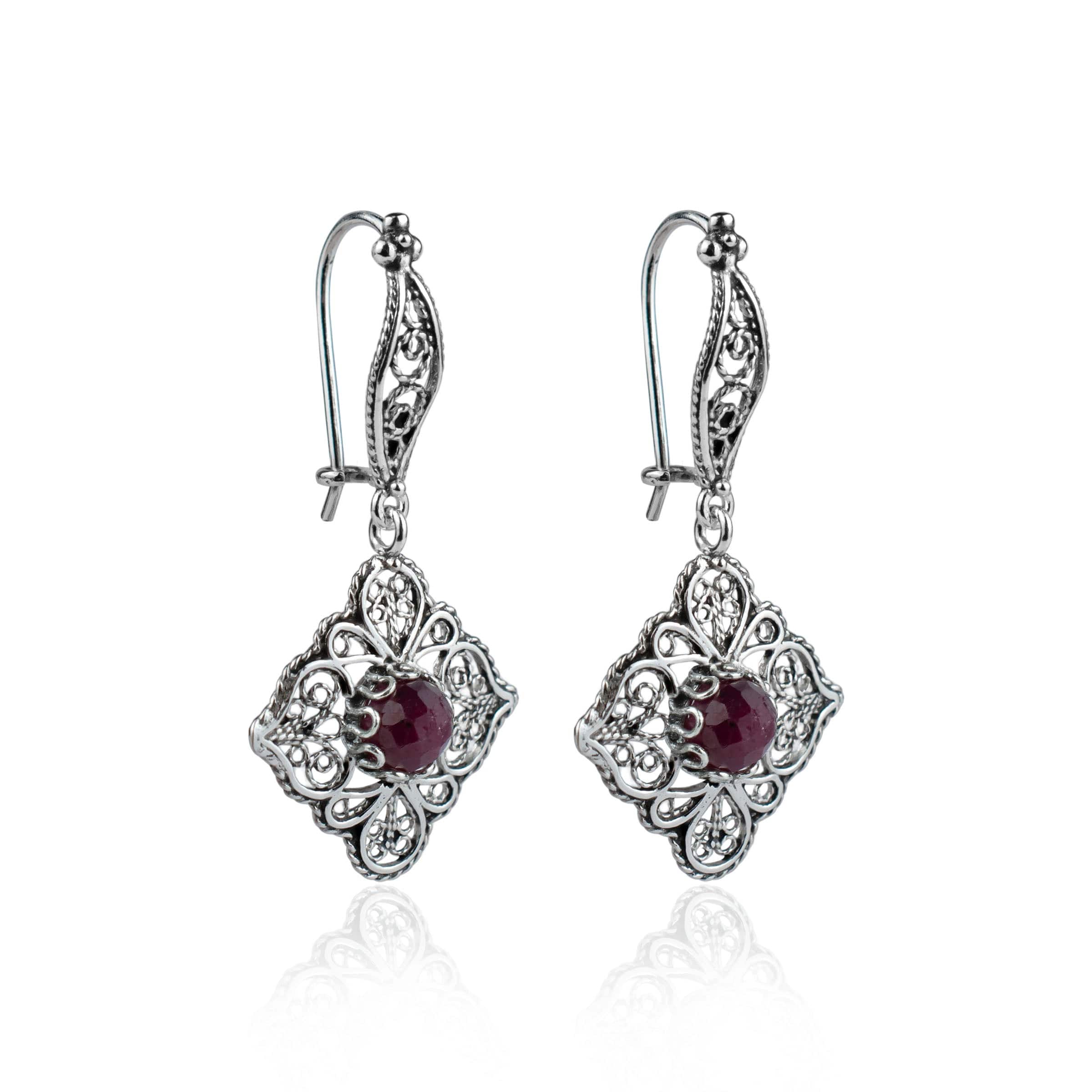 Elegant sterling silver dangle drop earrings featuring intricate filigree art and vibrant ruby corundum gemstones.