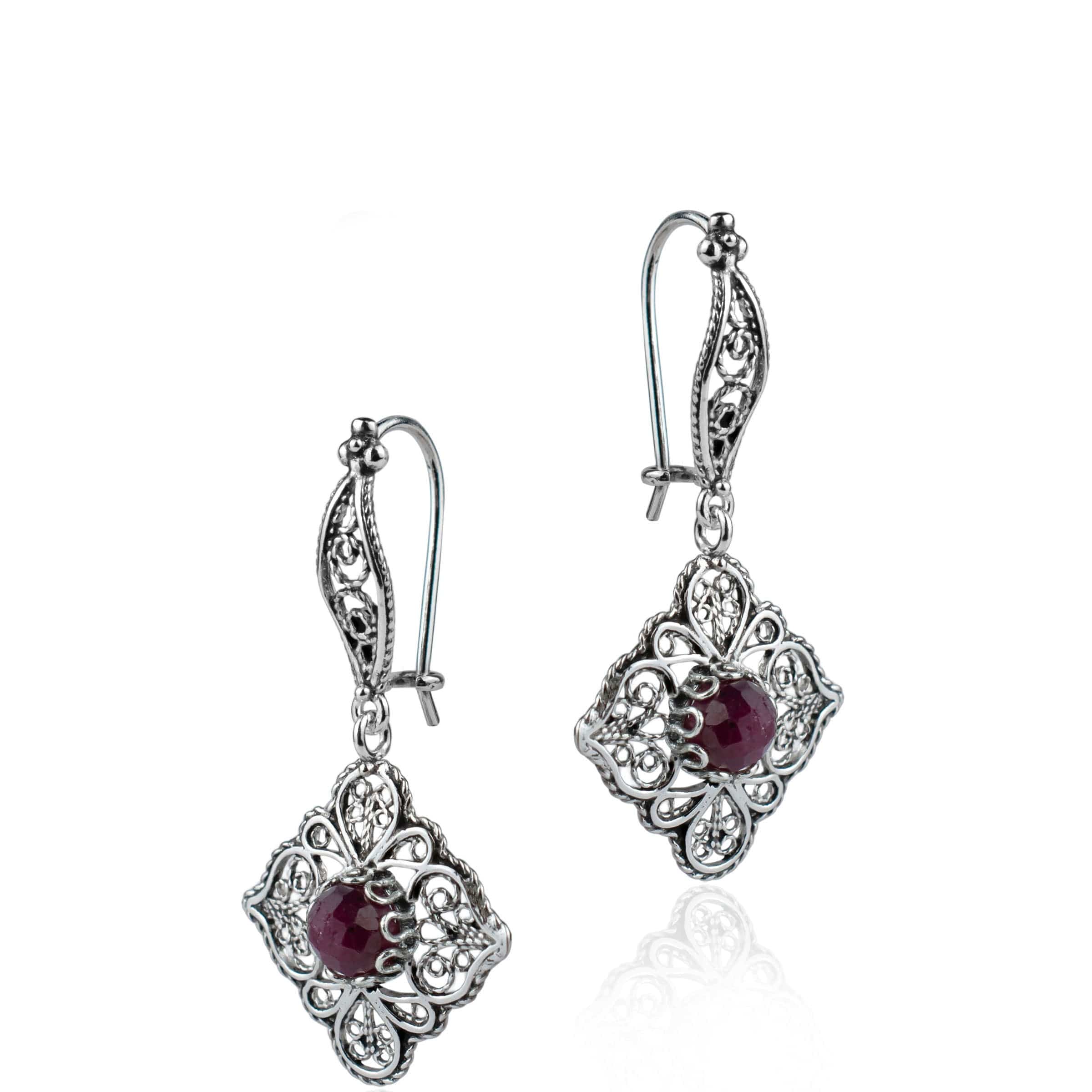 Elegant sterling silver dangle drop earrings featuring intricate filigree art and vibrant ruby corundum gemstones.