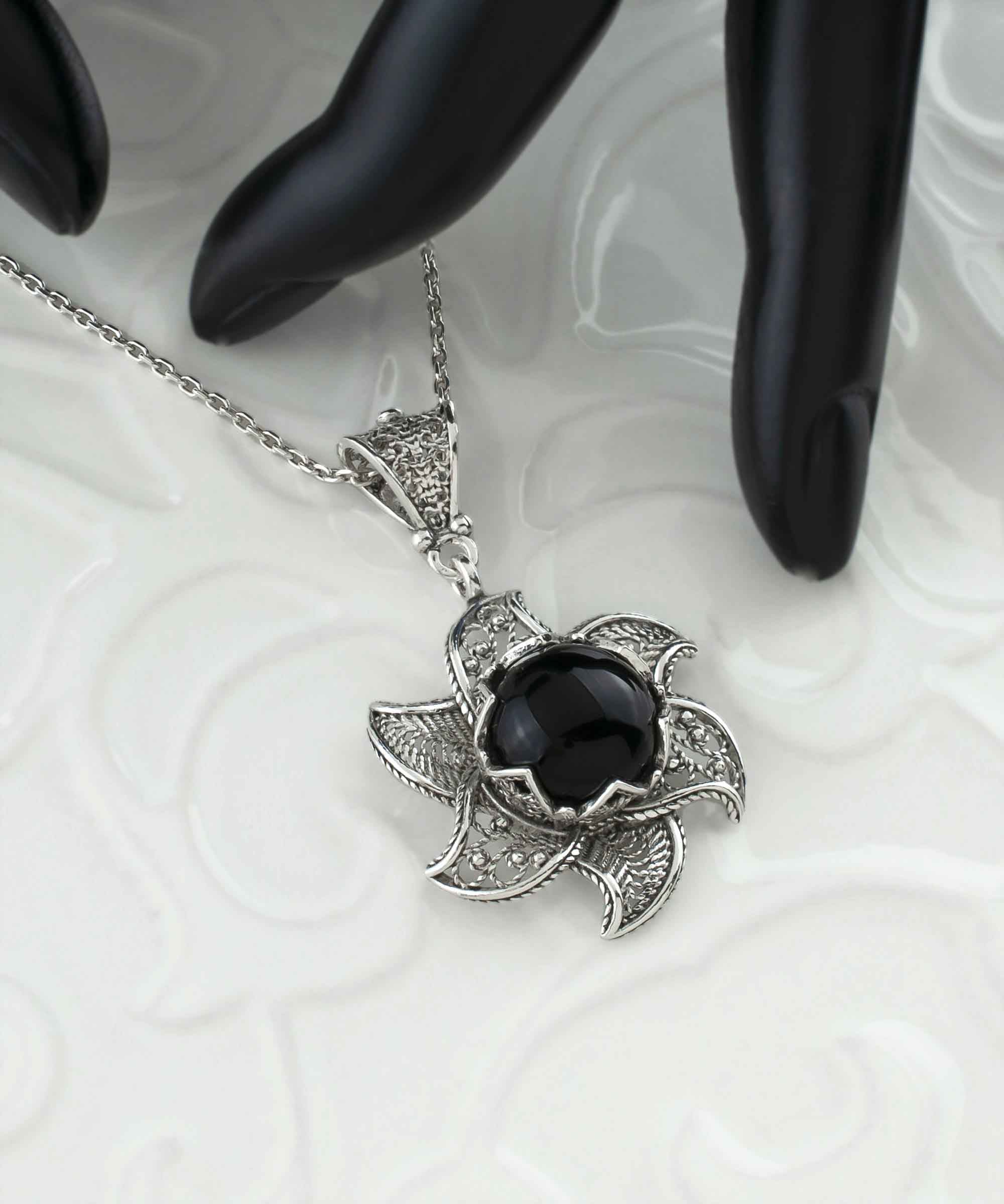 Sterling silver filigree necklace featuring a blossoming lotus flower pendant with a black onyx gemstone at the center, elegantly displayed.