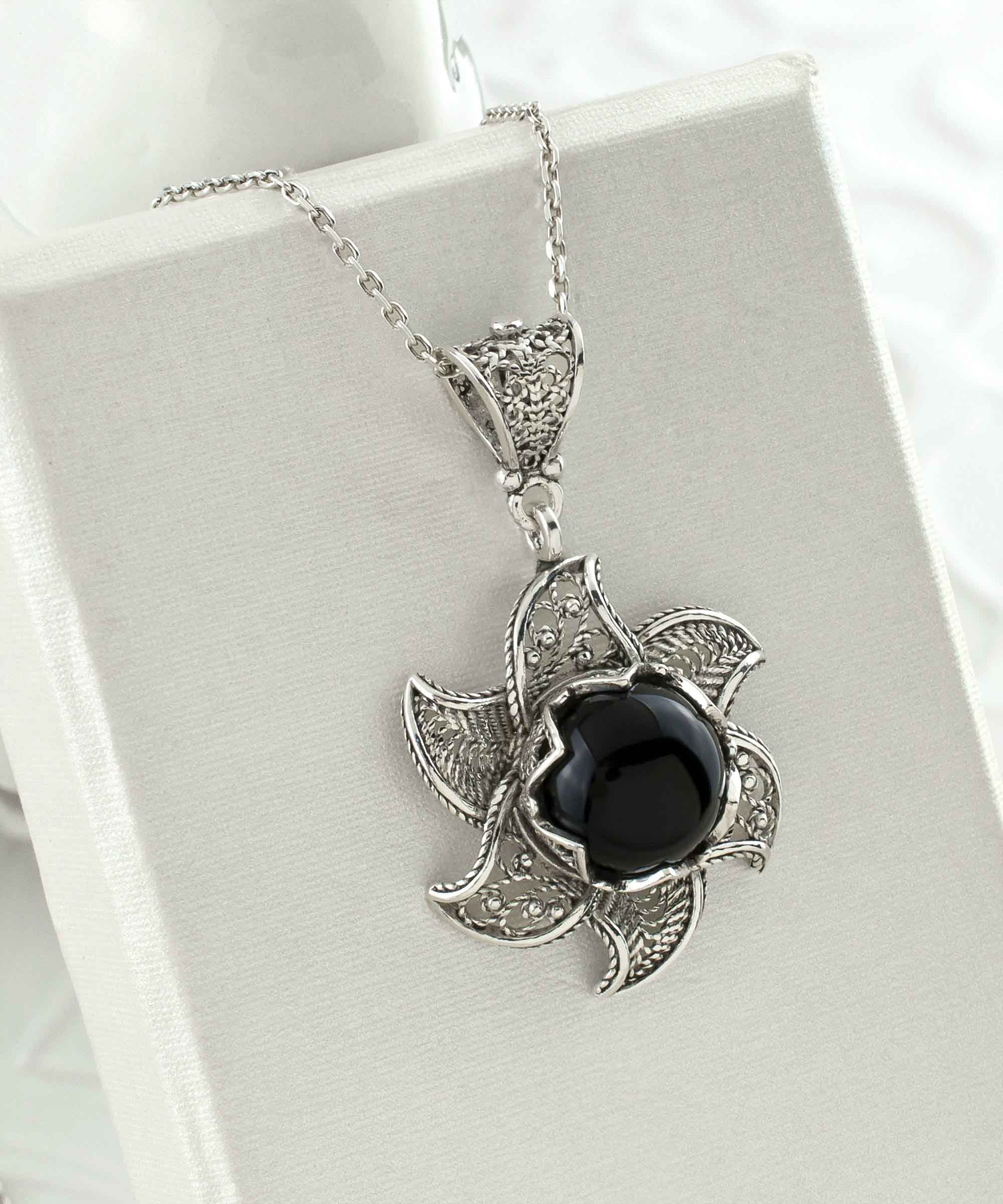 Sterling silver filigree necklace featuring a blossoming lotus flower pendant with a black onyx gemstone at the center, elegantly displayed.