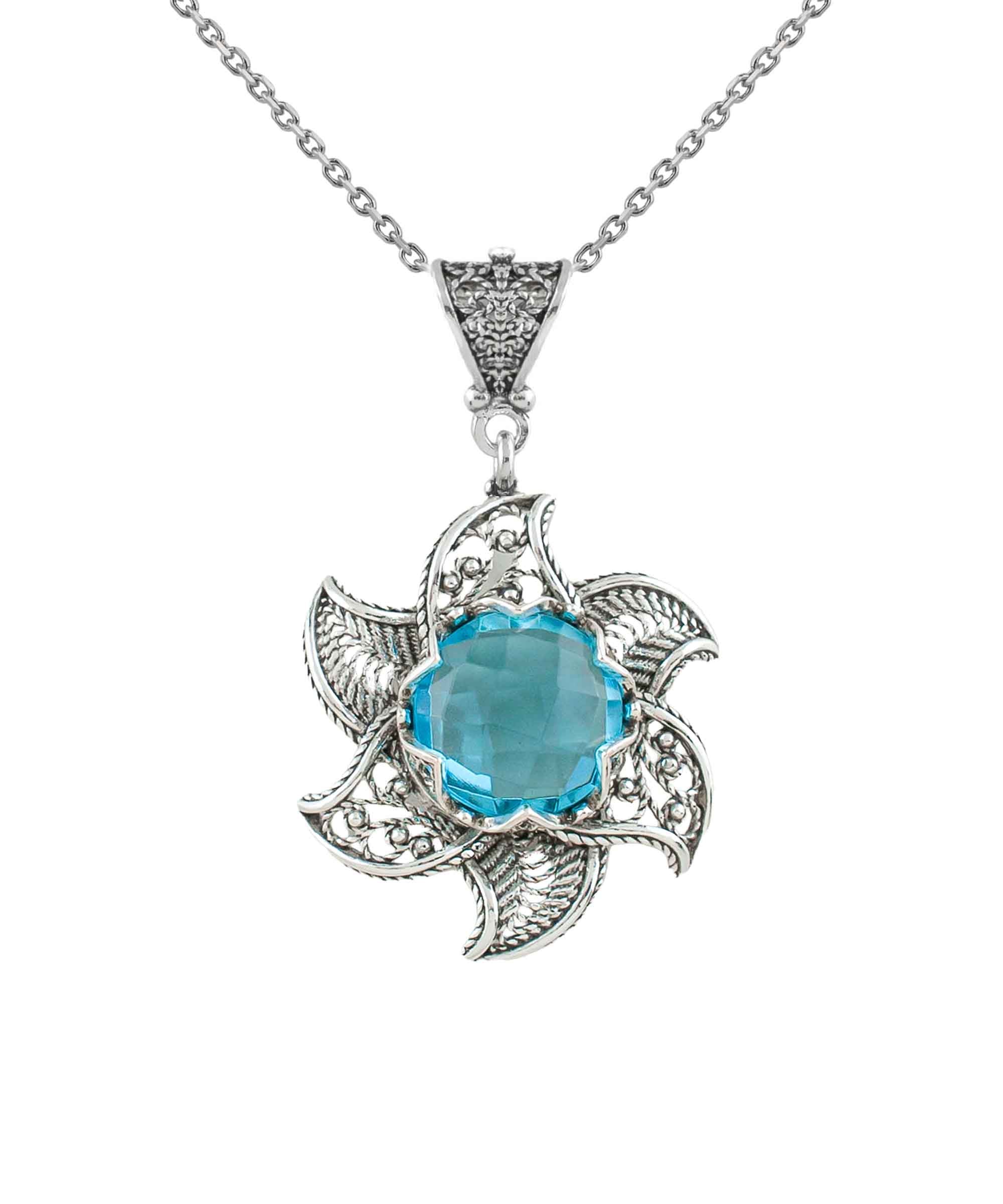 Sterling silver filigree lotus flower pendant with blue topaz gemstone, showcasing intricate design and elegant craftsmanship.