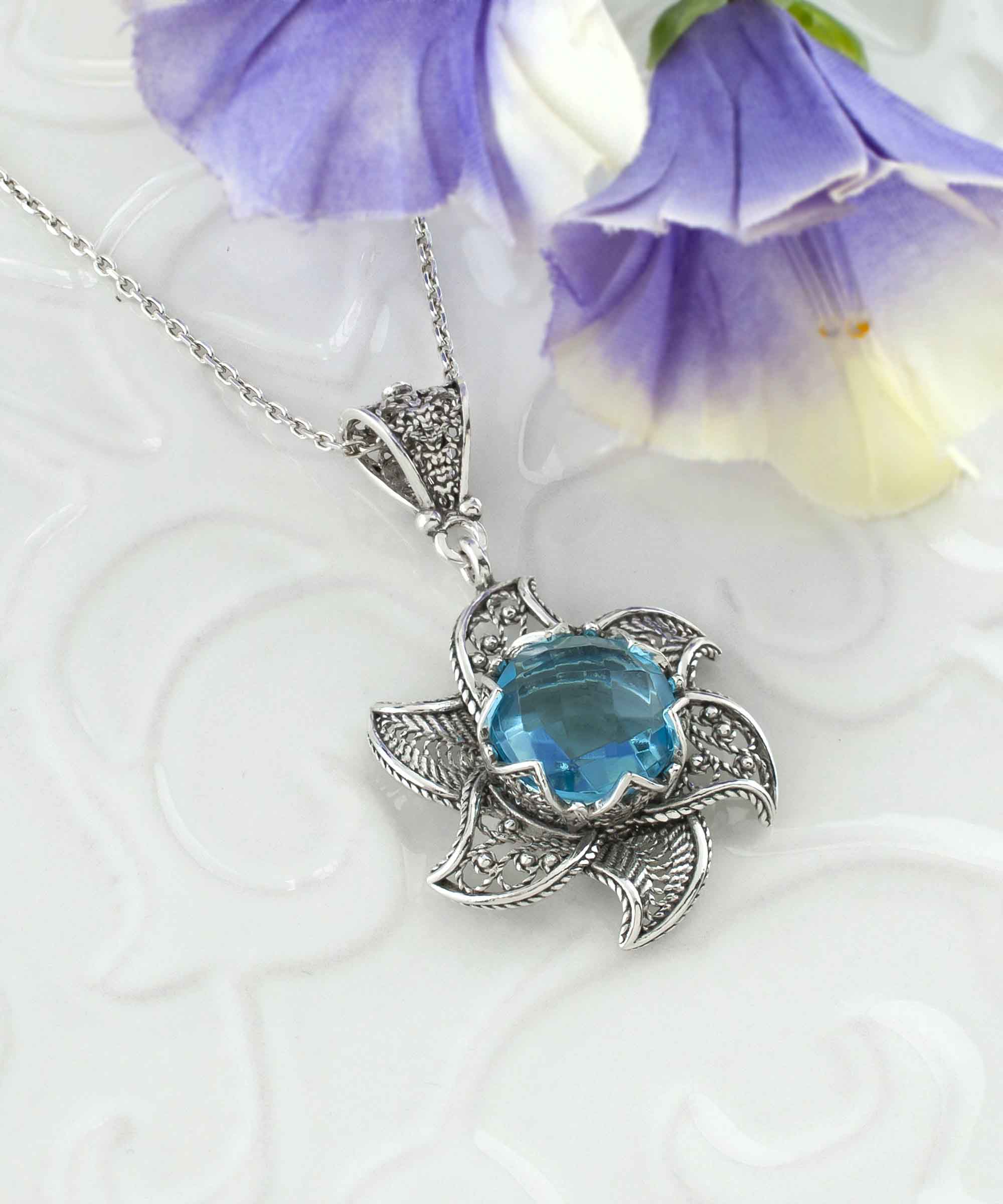 Sterling silver filigree lotus flower pendant with blue topaz gemstone, showcasing intricate design and elegant craftsmanship.