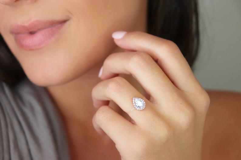 A stunning sterling silver ring featuring a pear-shaped cubic zirconia surrounded by a halo of sparkling CZs, designed to appear as if floating on the finger.