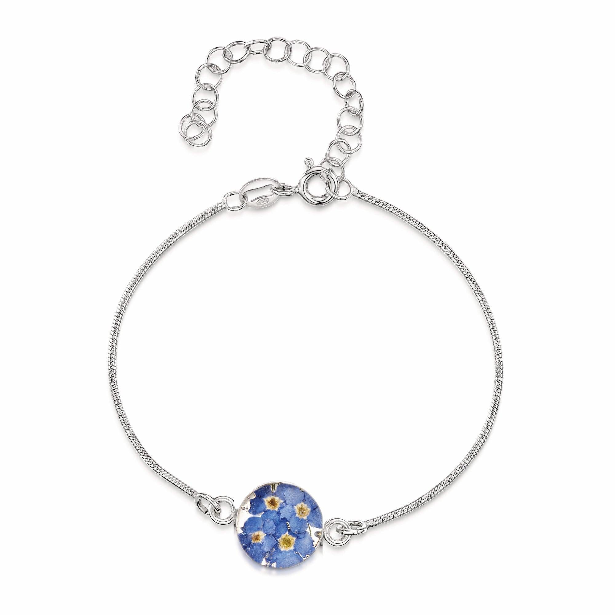 Sterling silver snake bracelet featuring a round charm with delicate blue forget-me-not flowers set in resin, elegantly displayed in a gift box.