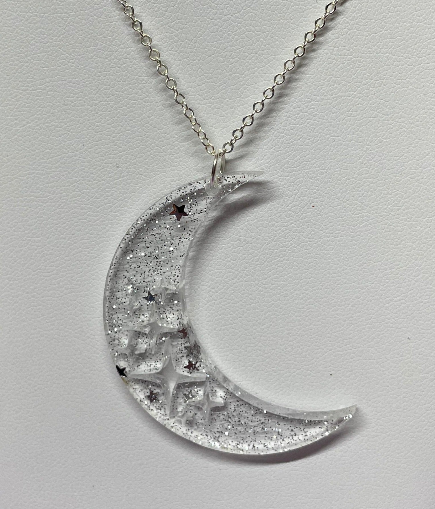 Stevie Moon Necklace featuring a moon shape with cut-out stars on a sterling silver chain, showcasing its unique design and craftsmanship.