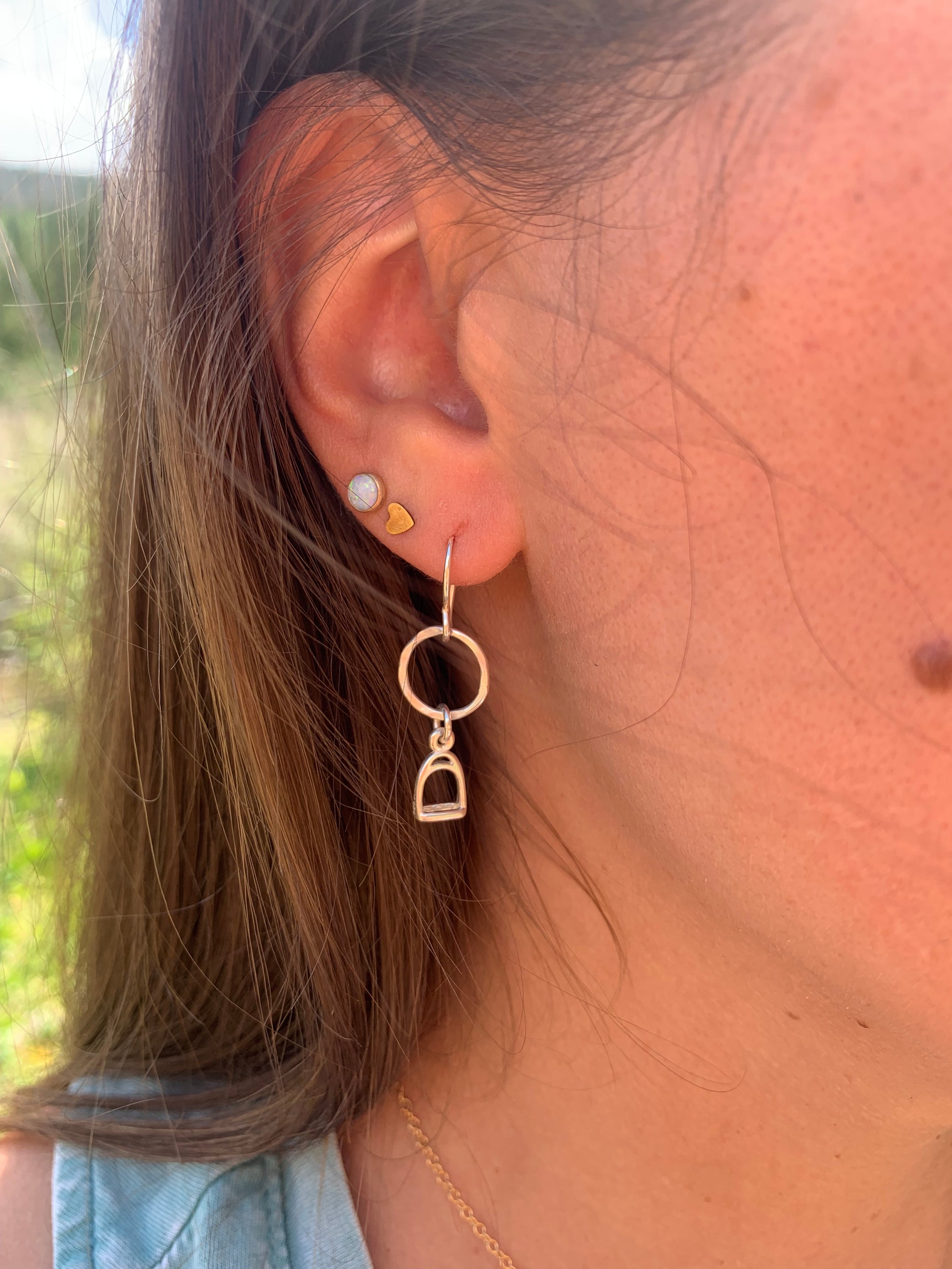 A pair of handmade Stirrup Drop Earrings featuring stirrup charms hanging from a hammered circle, crafted from recycled sterling silver.