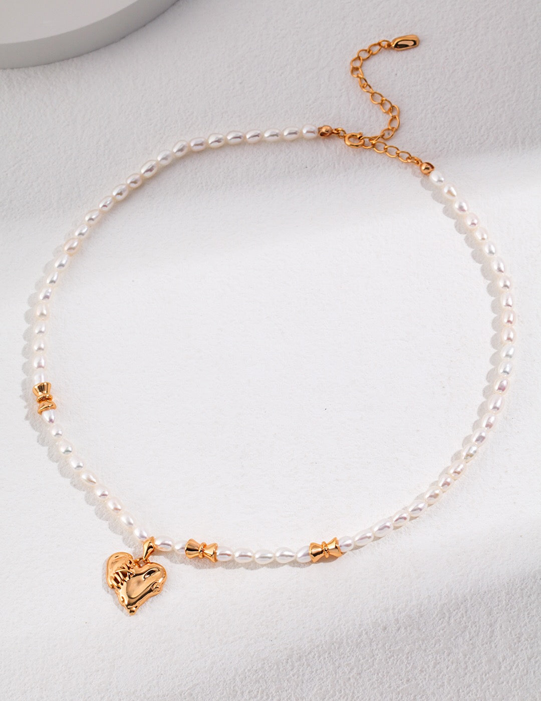 A stunning Stitched Heart-Shaped Pearl Pendant Necklace featuring natural pearls and gold vermeil, elegantly displayed on a soft background.