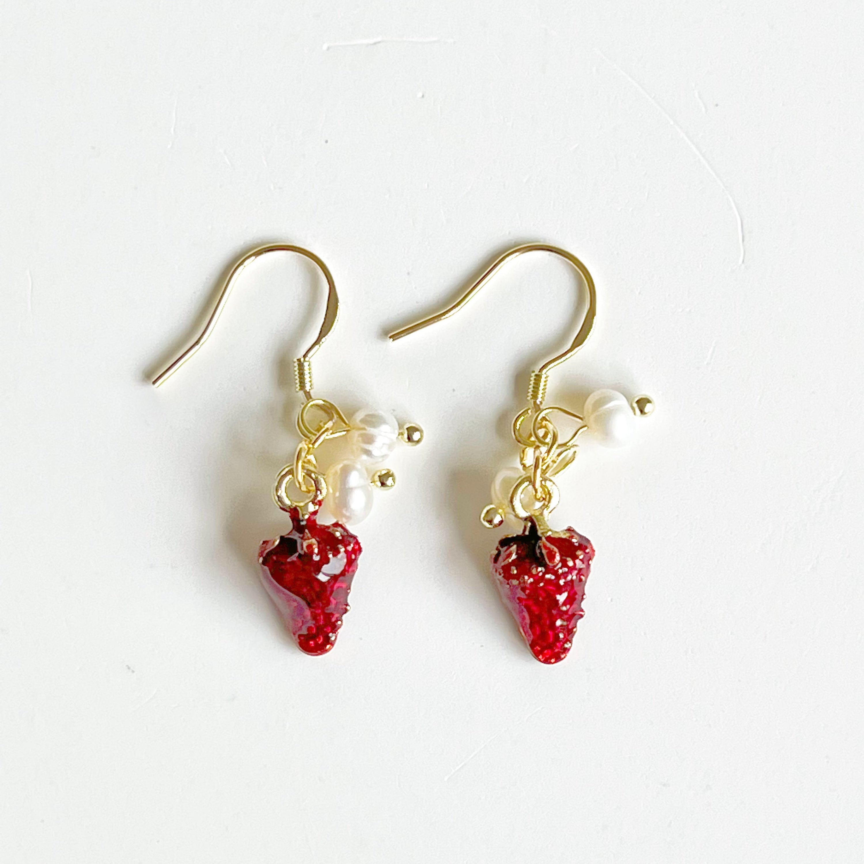 A pair of Strawberry and Pearl Mini Drop Earrings featuring vibrant strawberry designs and elegant freshwater pearls, set in gold-plated materials.