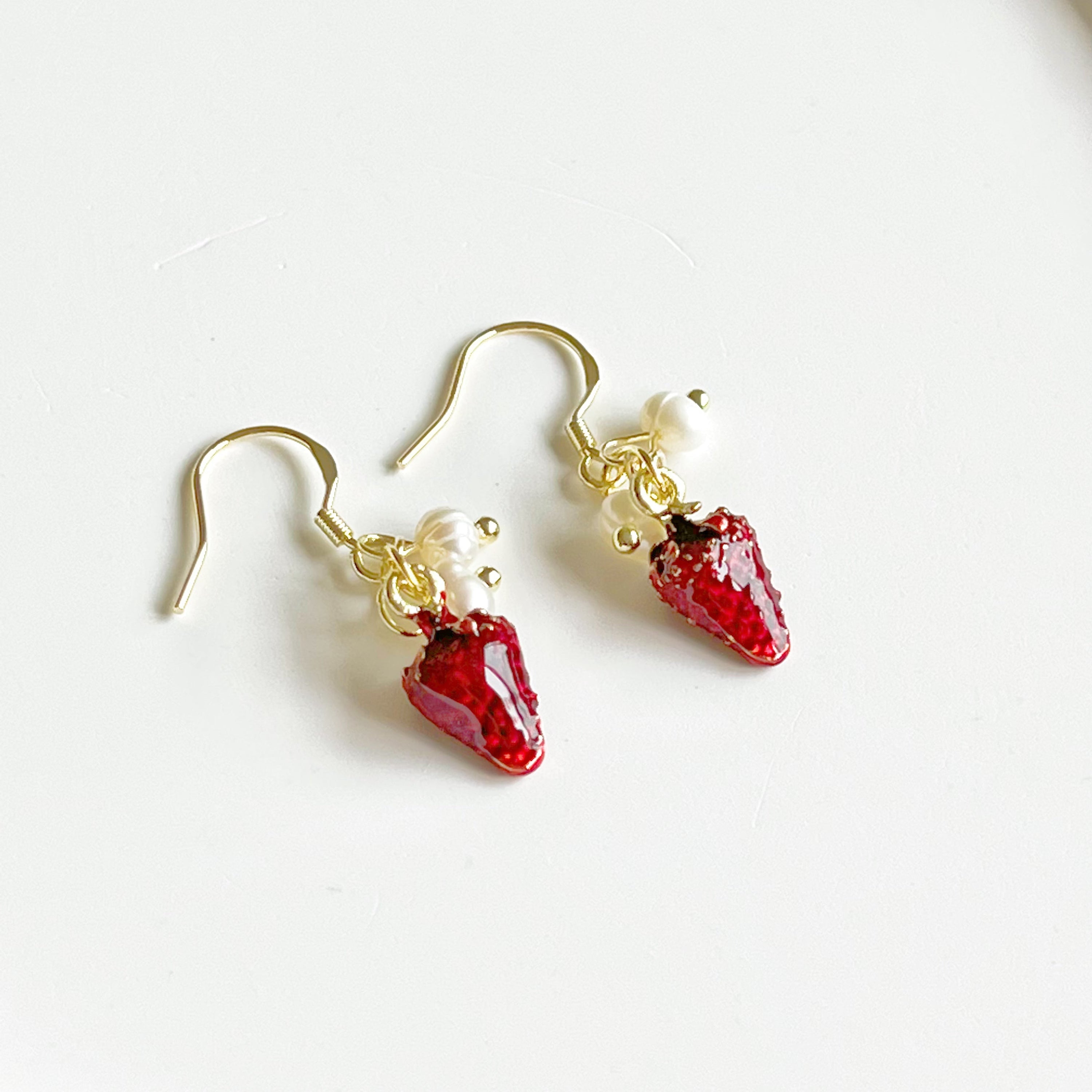 A pair of Strawberry and Pearl Mini Drop Earrings featuring vibrant strawberry designs and elegant freshwater pearls, set in gold-plated materials.