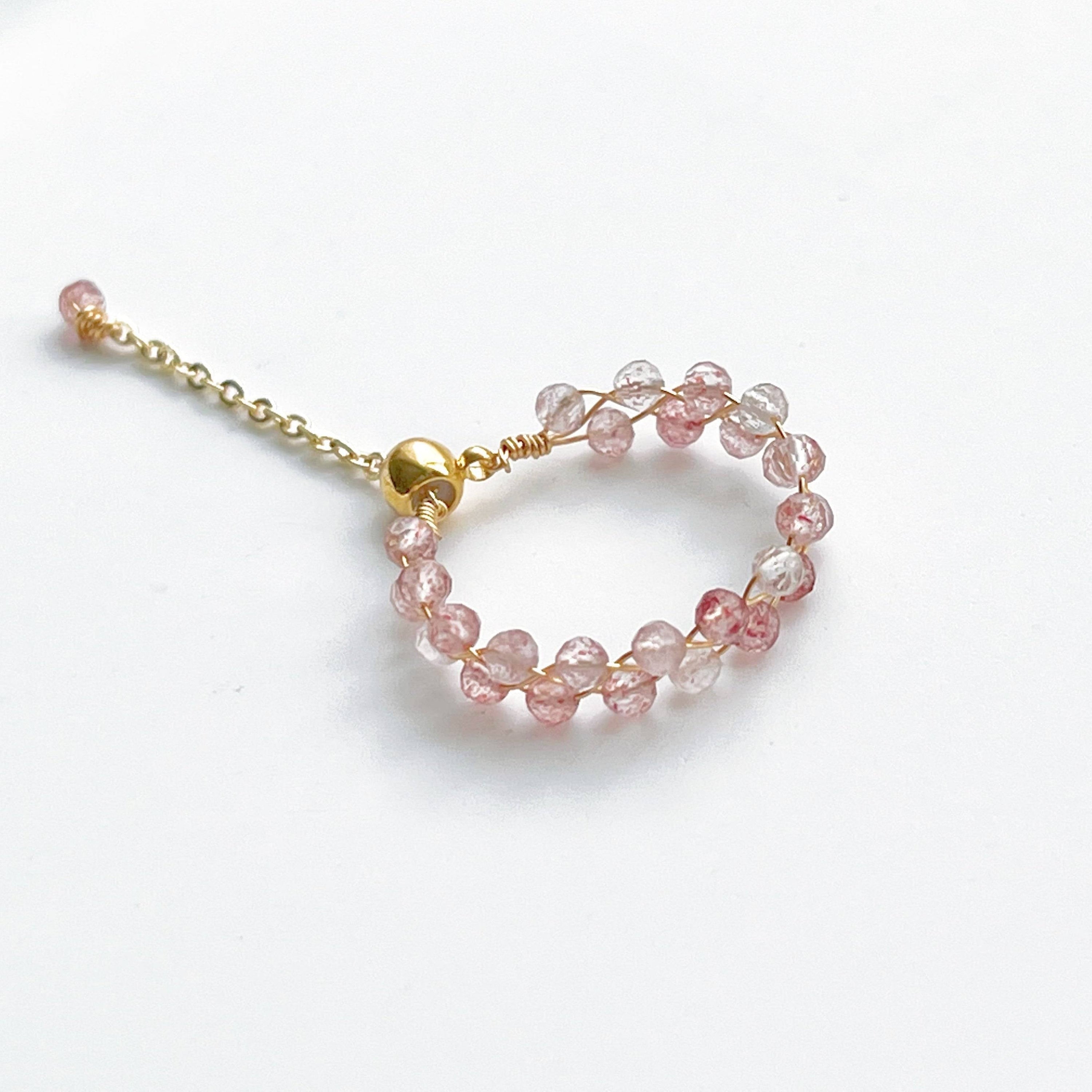 A handmade adjustable ring featuring natural strawberry quartz beads, elegantly designed with gold-plated bronze wire.