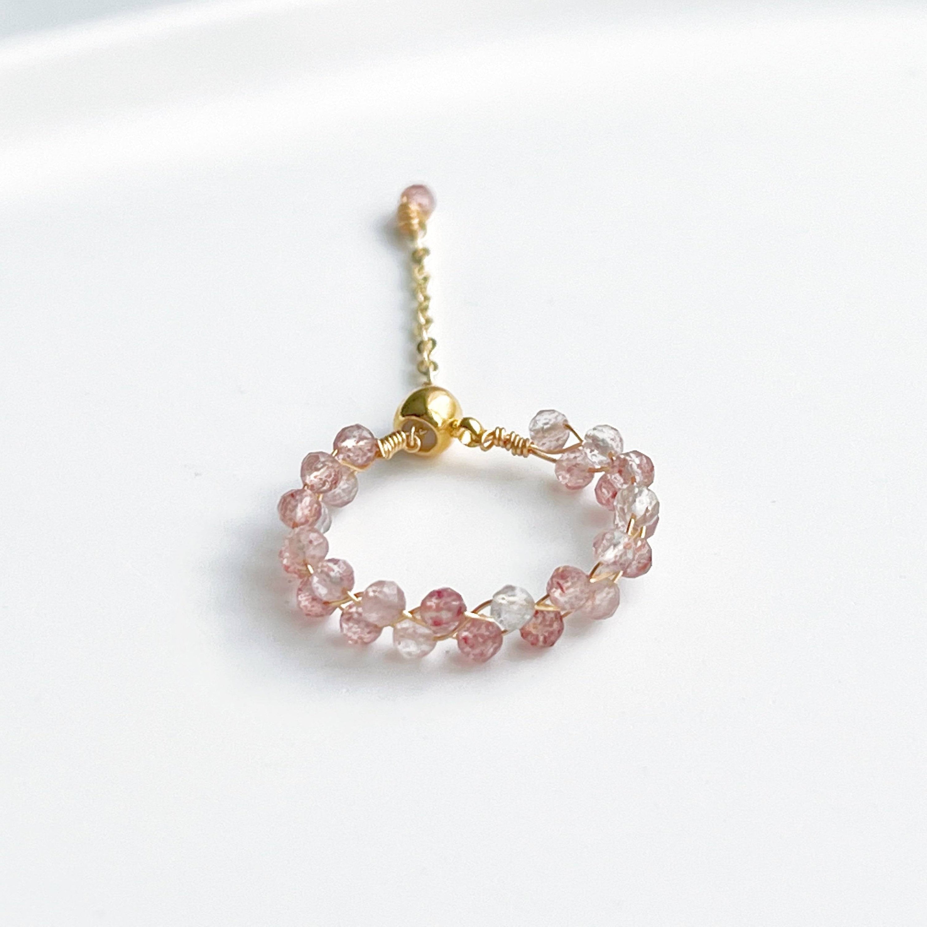 A handmade adjustable ring featuring natural strawberry quartz beads, elegantly designed with gold-plated bronze wire.