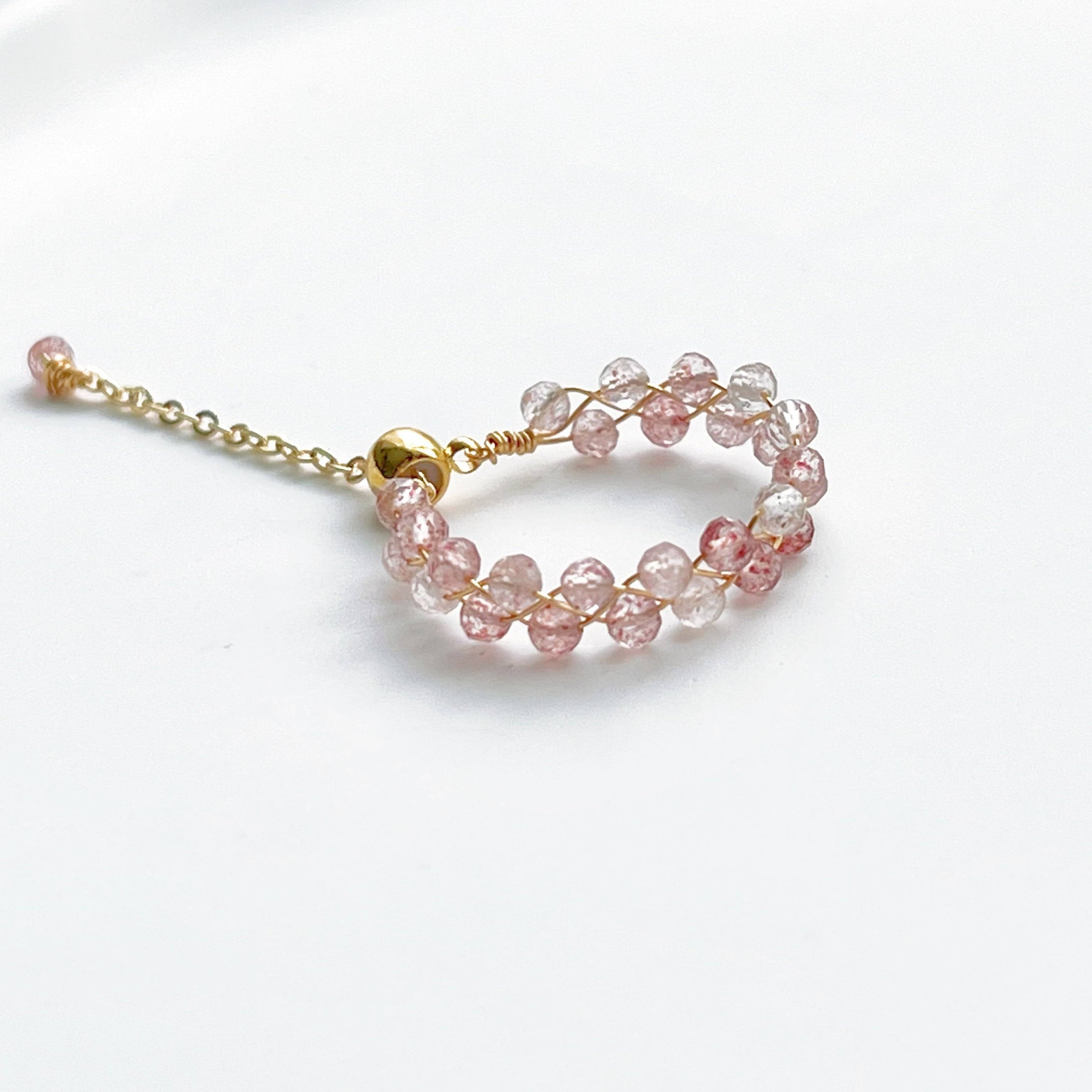 A handmade adjustable ring featuring natural strawberry quartz beads, elegantly designed with gold-plated bronze wire.