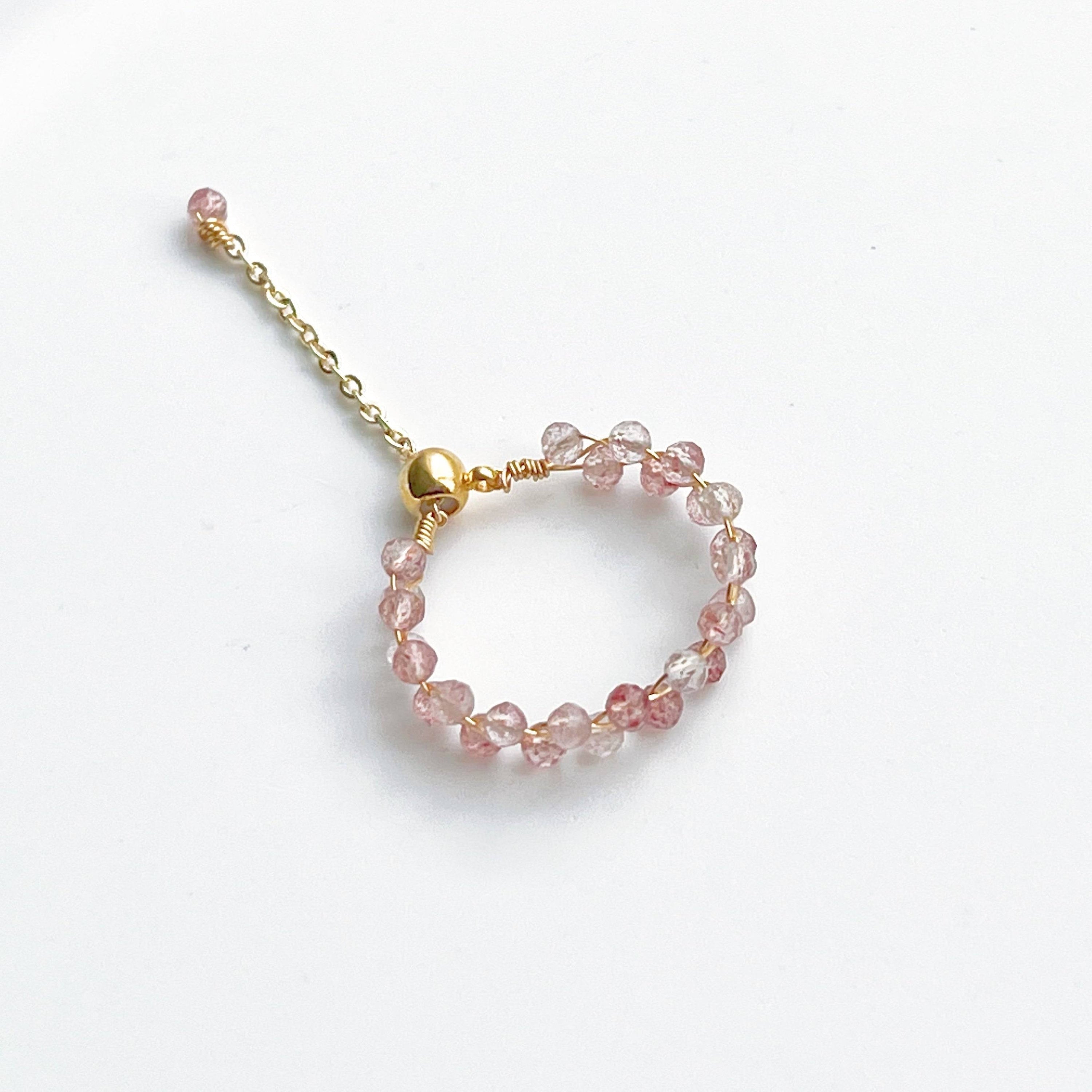 A handmade adjustable ring featuring natural strawberry quartz beads, elegantly designed with gold-plated bronze wire.