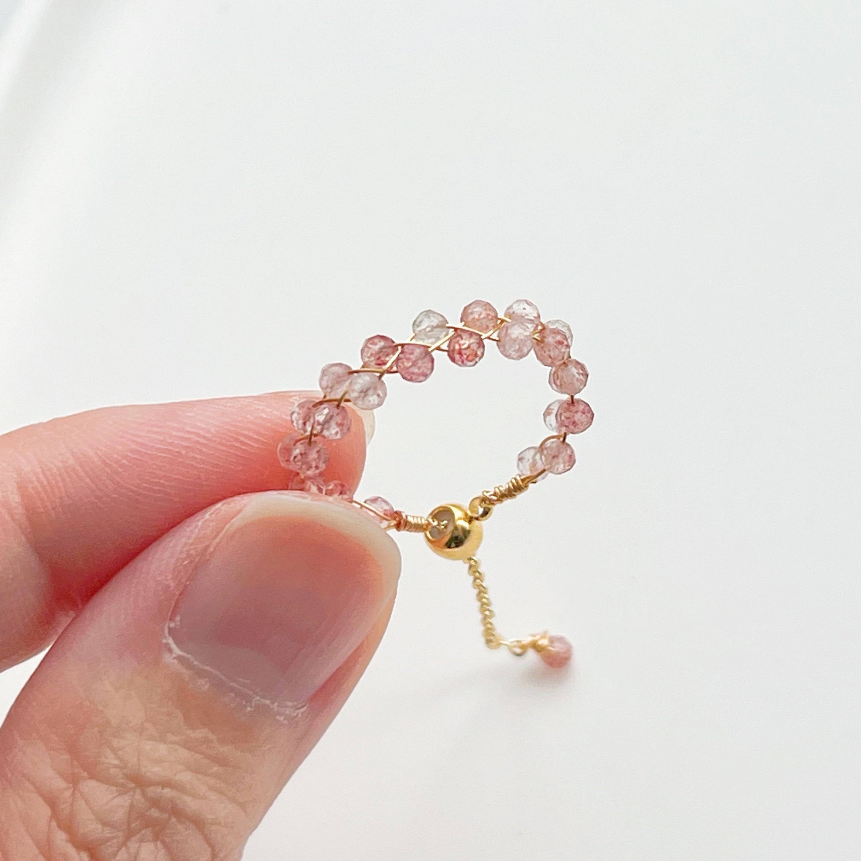 A handmade adjustable ring featuring natural strawberry quartz beads, elegantly designed with gold-plated bronze wire.