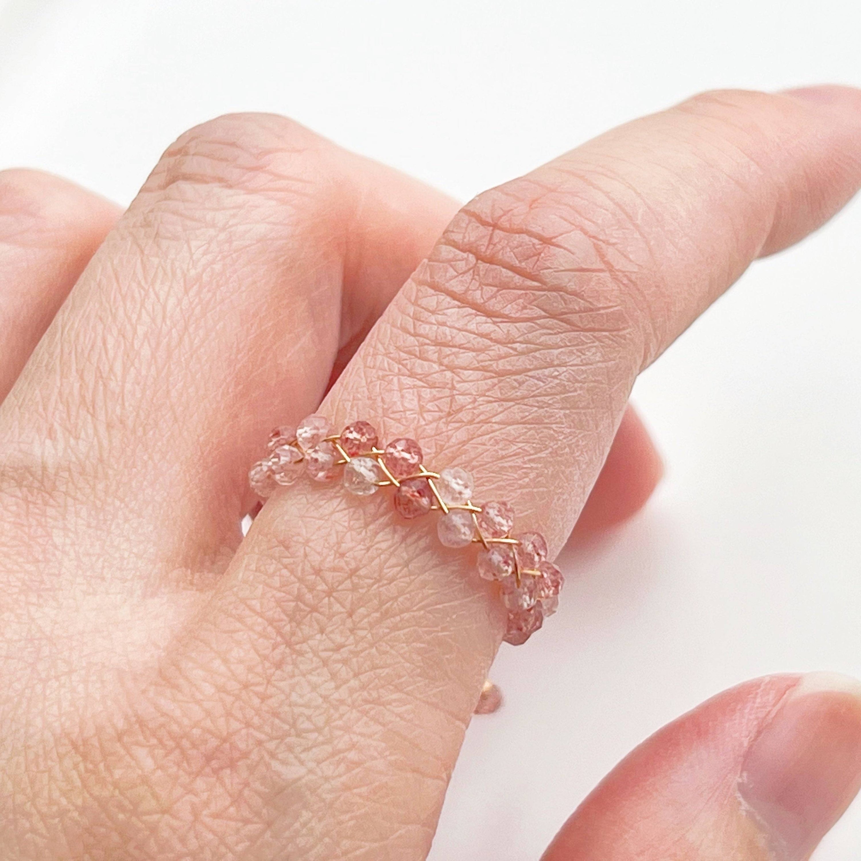 A handmade adjustable ring featuring natural strawberry quartz beads, elegantly designed with gold-plated bronze wire.