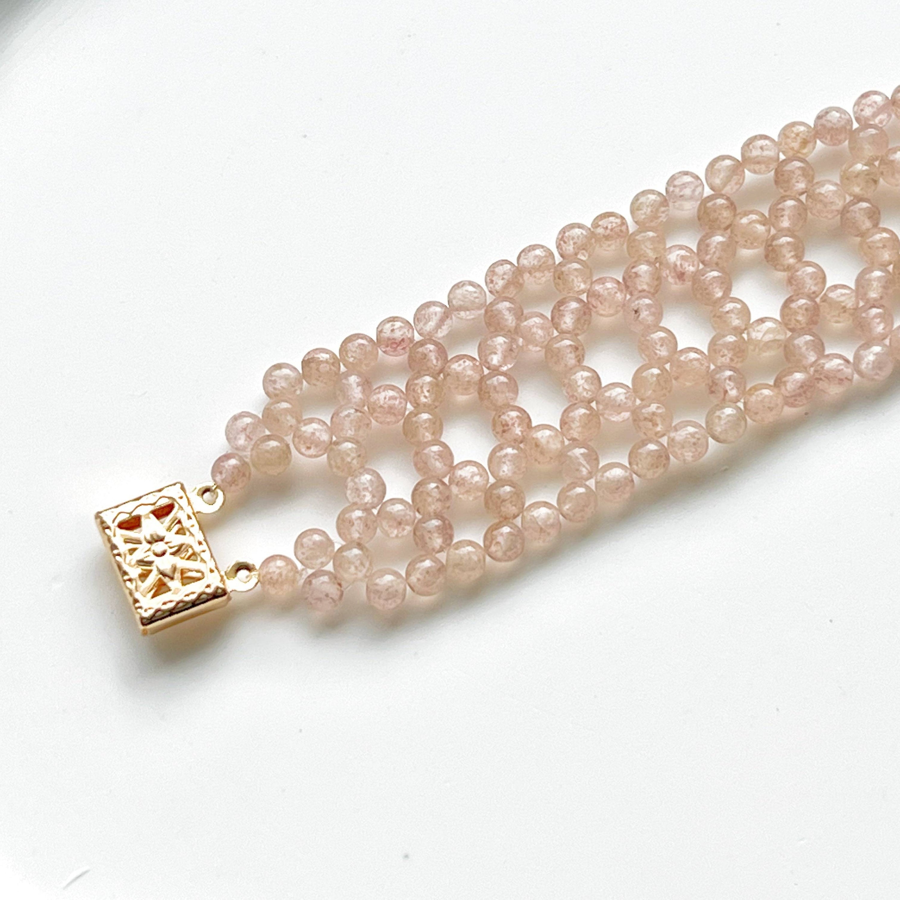 A handmade cuff bracelet featuring mini strawberry quartz beads, showcasing a gold plated bronze buckle, perfect for adding a touch of elegance.