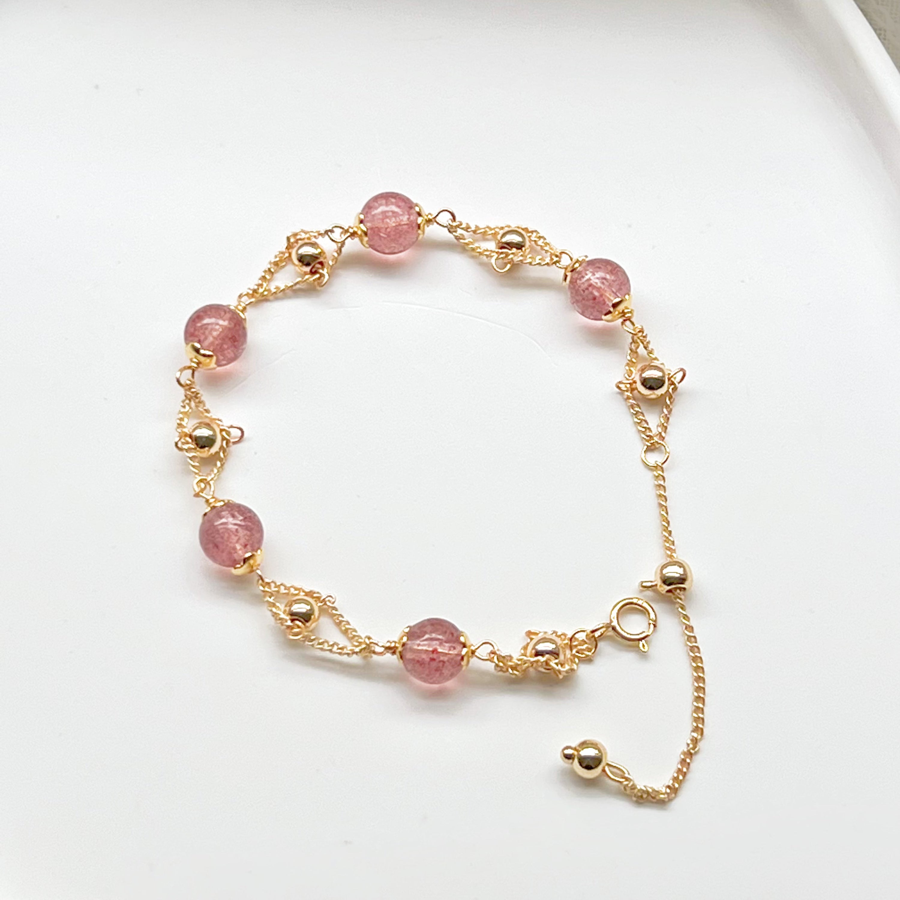 A delicate Strawberry Quartz Gold Beads Bracelet featuring natural pink quartz beads and gold plated bronze accents, elegantly displayed.