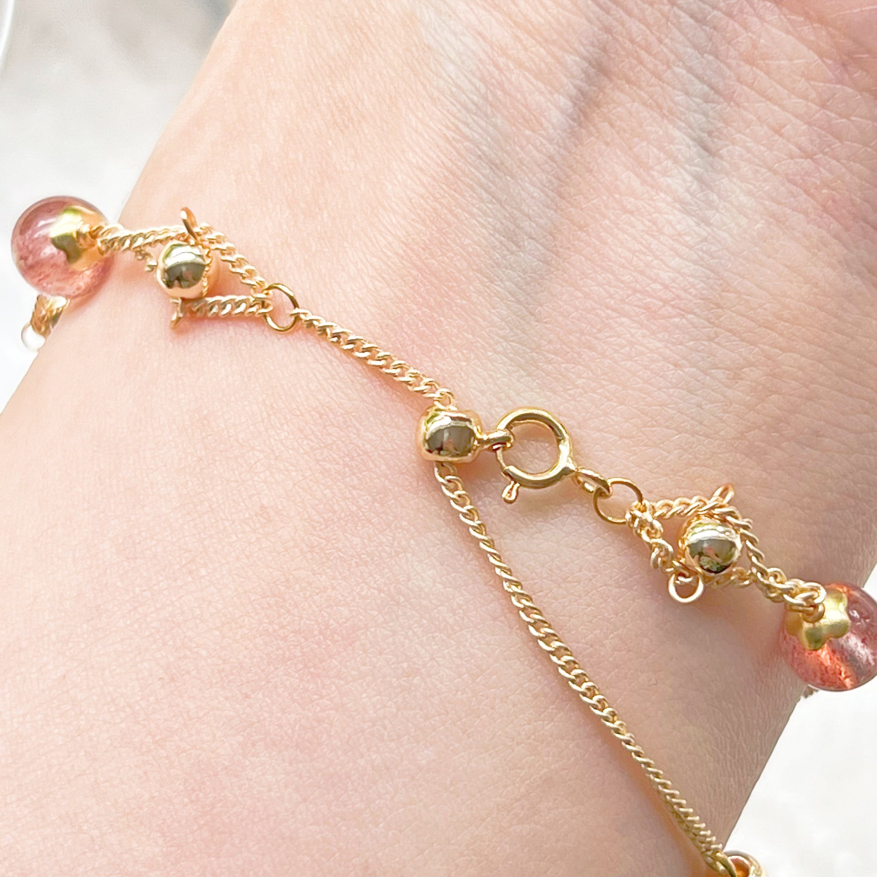 A delicate Strawberry Quartz Gold Beads Bracelet featuring natural pink quartz beads and gold plated bronze accents, elegantly displayed.