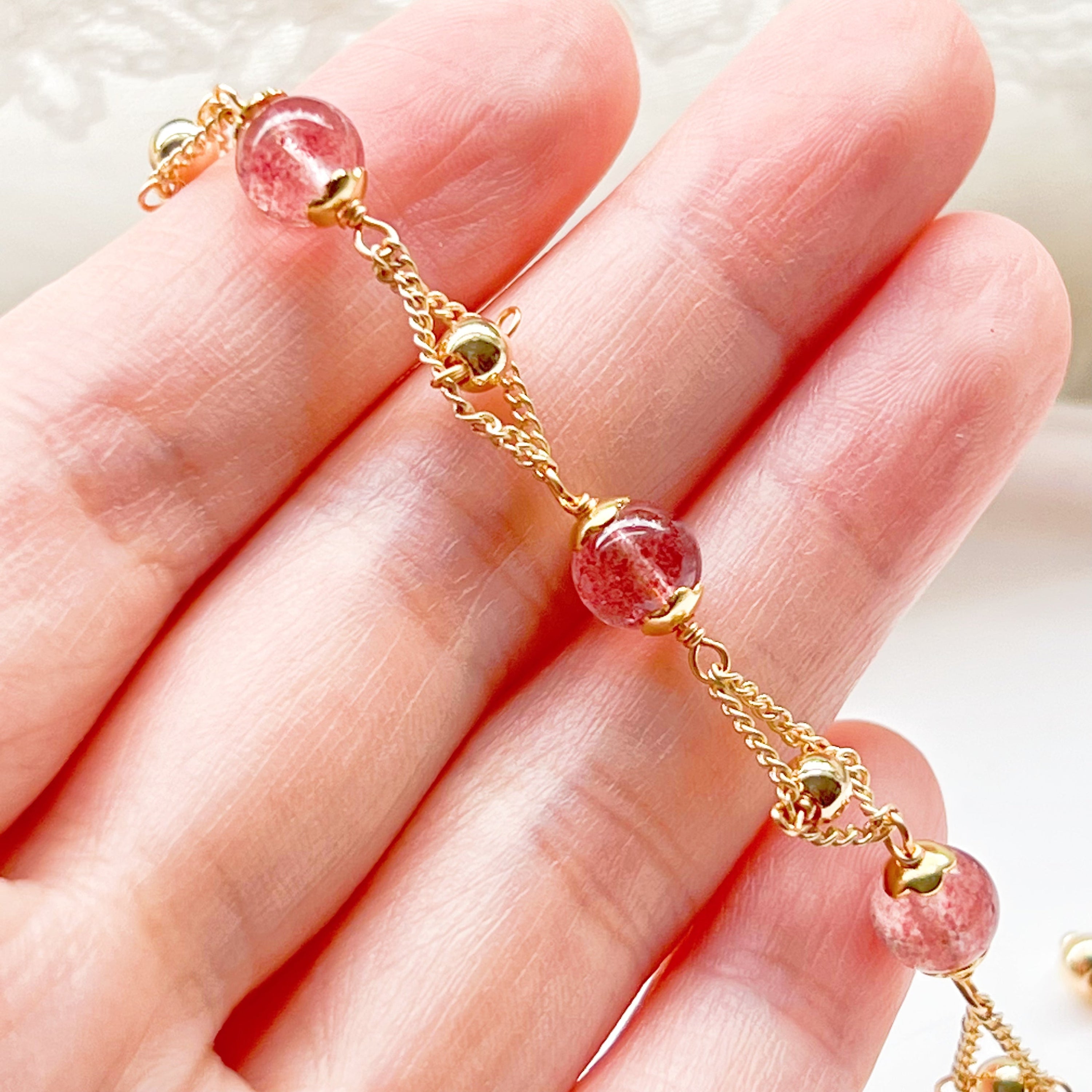 A delicate Strawberry Quartz Gold Beads Bracelet featuring natural pink quartz beads and gold plated bronze accents, elegantly displayed.