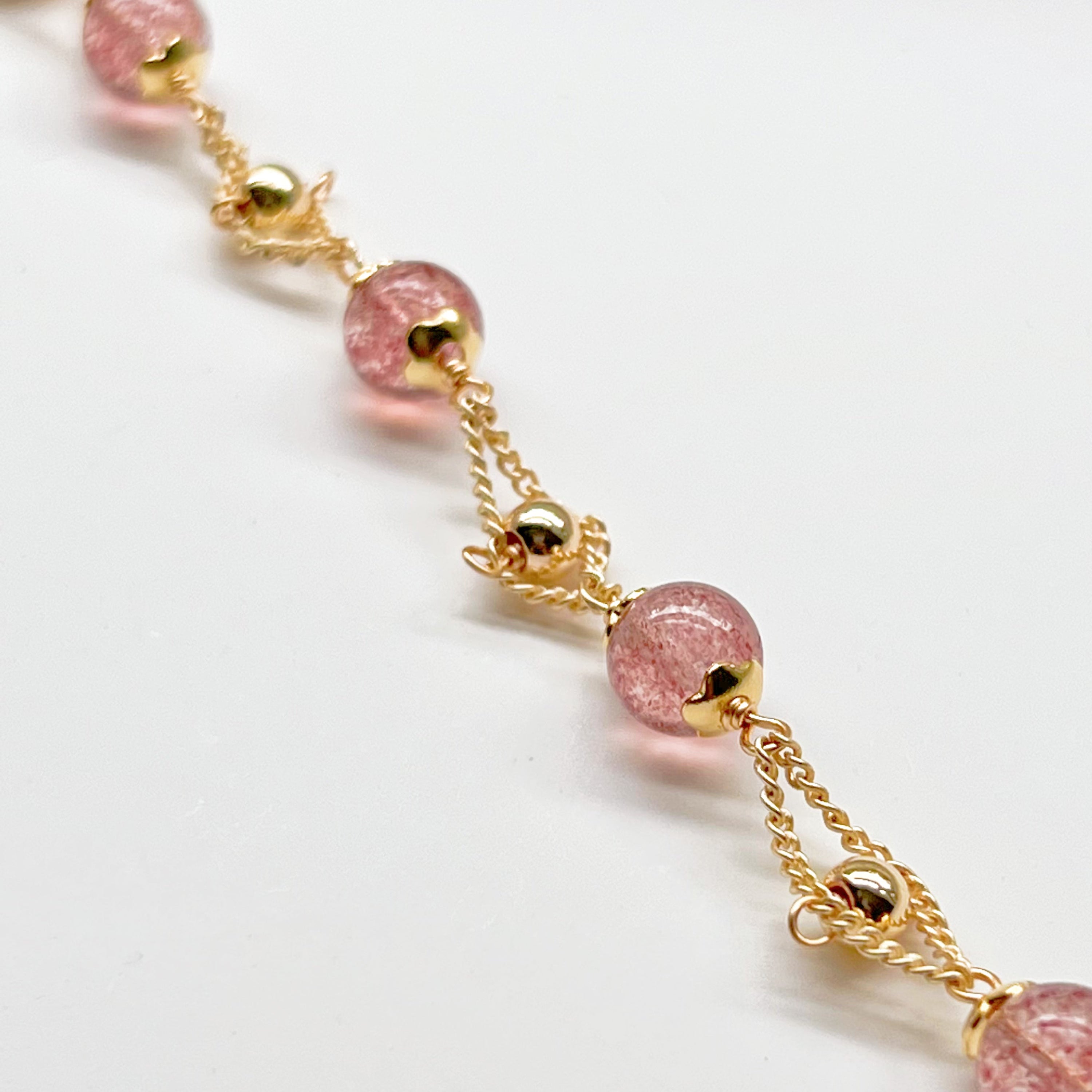 A delicate Strawberry Quartz Gold Beads Bracelet featuring natural pink quartz beads and gold plated bronze accents, elegantly displayed.