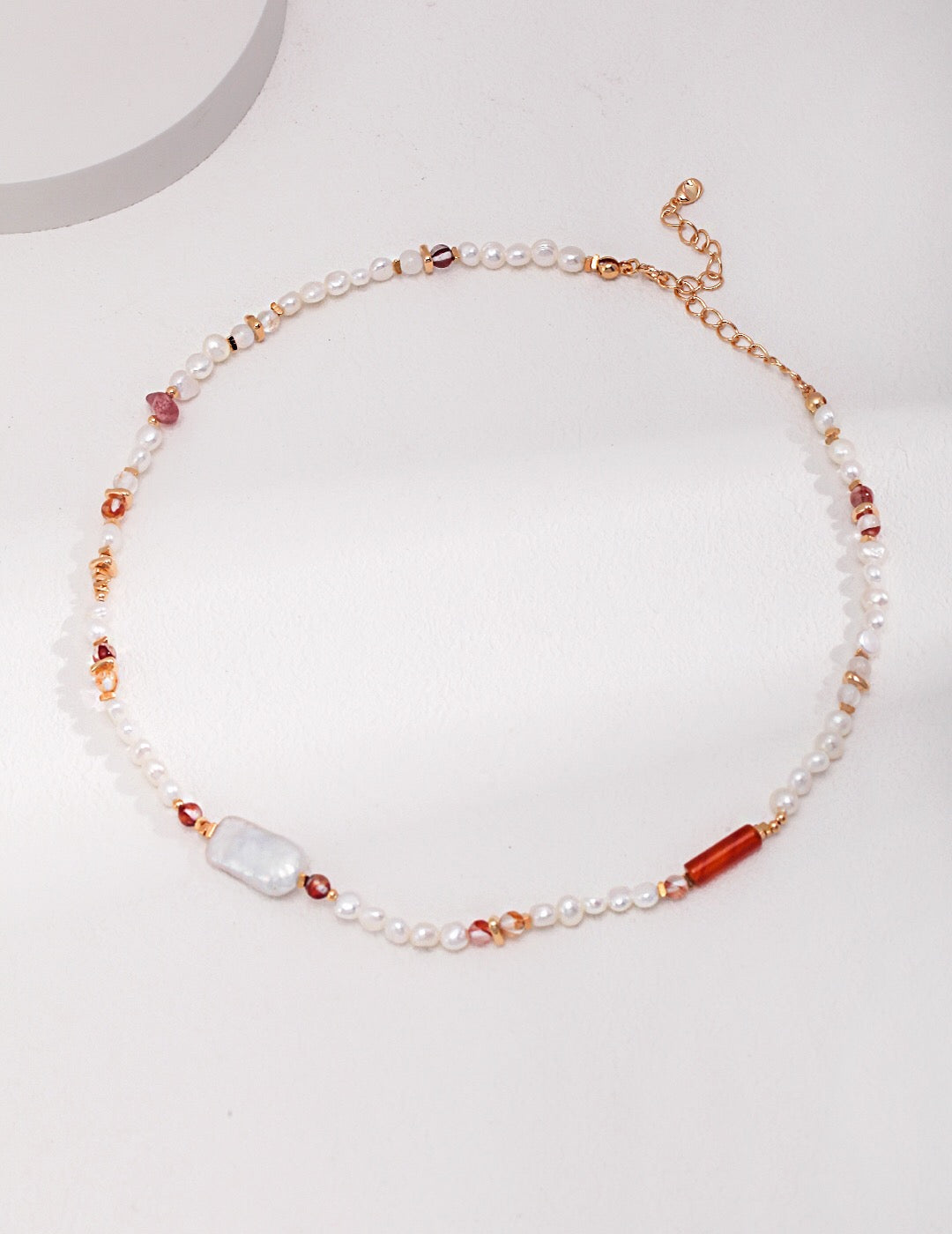 A handmade necklace featuring strawberry quartz beads and baroque pearls, elegantly designed with gold vermeil accents.