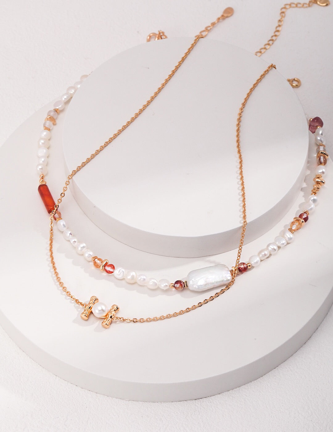 A handmade necklace featuring strawberry quartz beads and baroque pearls, elegantly designed with gold vermeil accents.