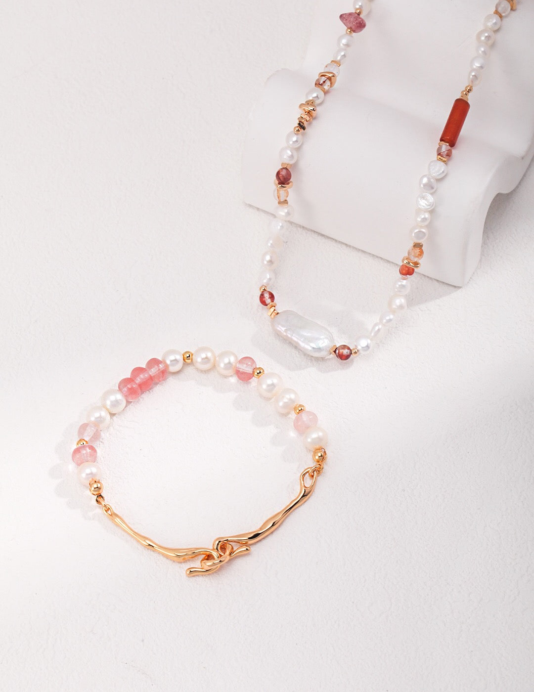 A handmade necklace featuring strawberry quartz beads and baroque pearls, elegantly designed with gold vermeil accents.