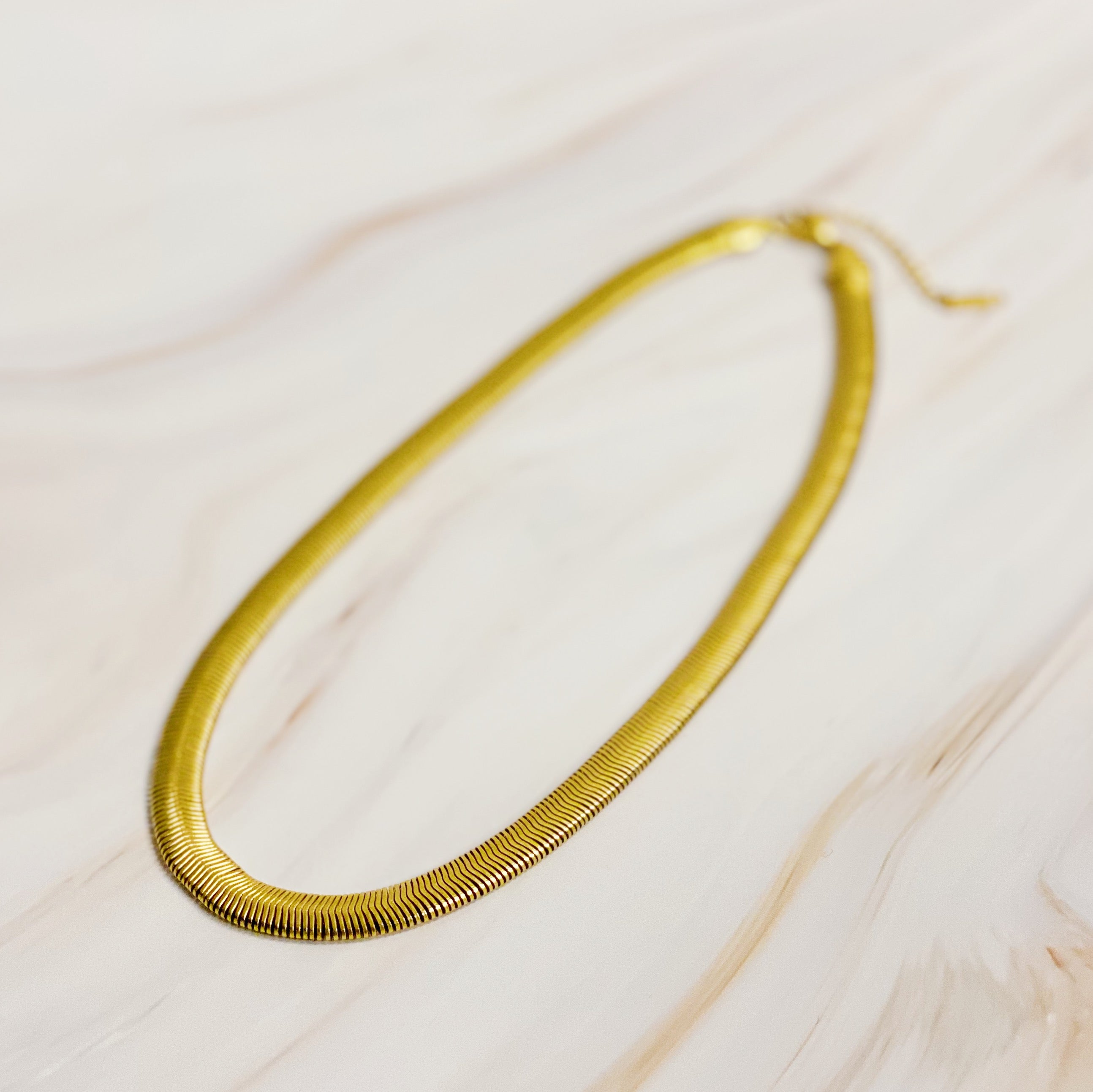 A stylish gold plated herringbone chain necklace with a 16-inch length and 2-inch extender, showcasing its elegant design.