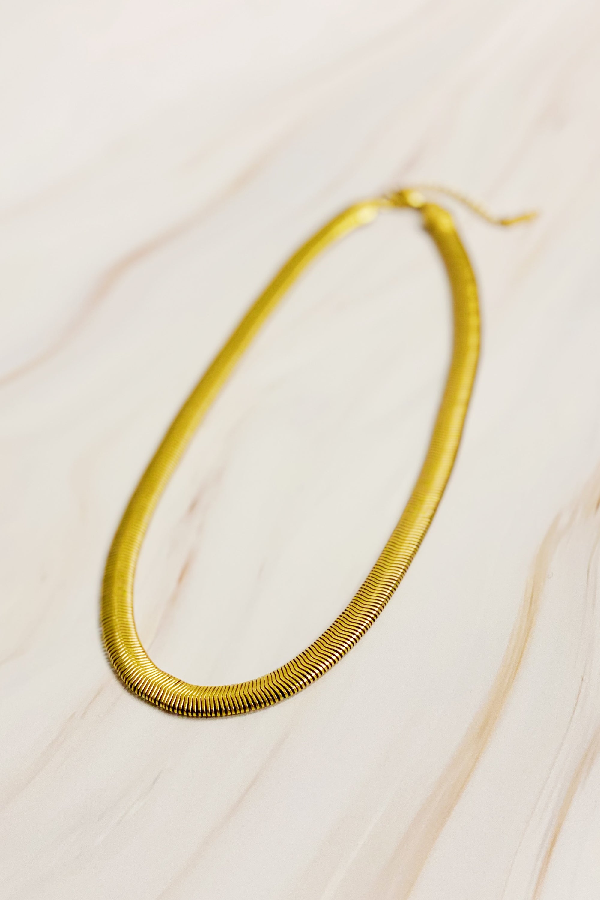 A stylish gold plated herringbone chain necklace with a 16-inch length and 2-inch extender, showcasing its elegant design.