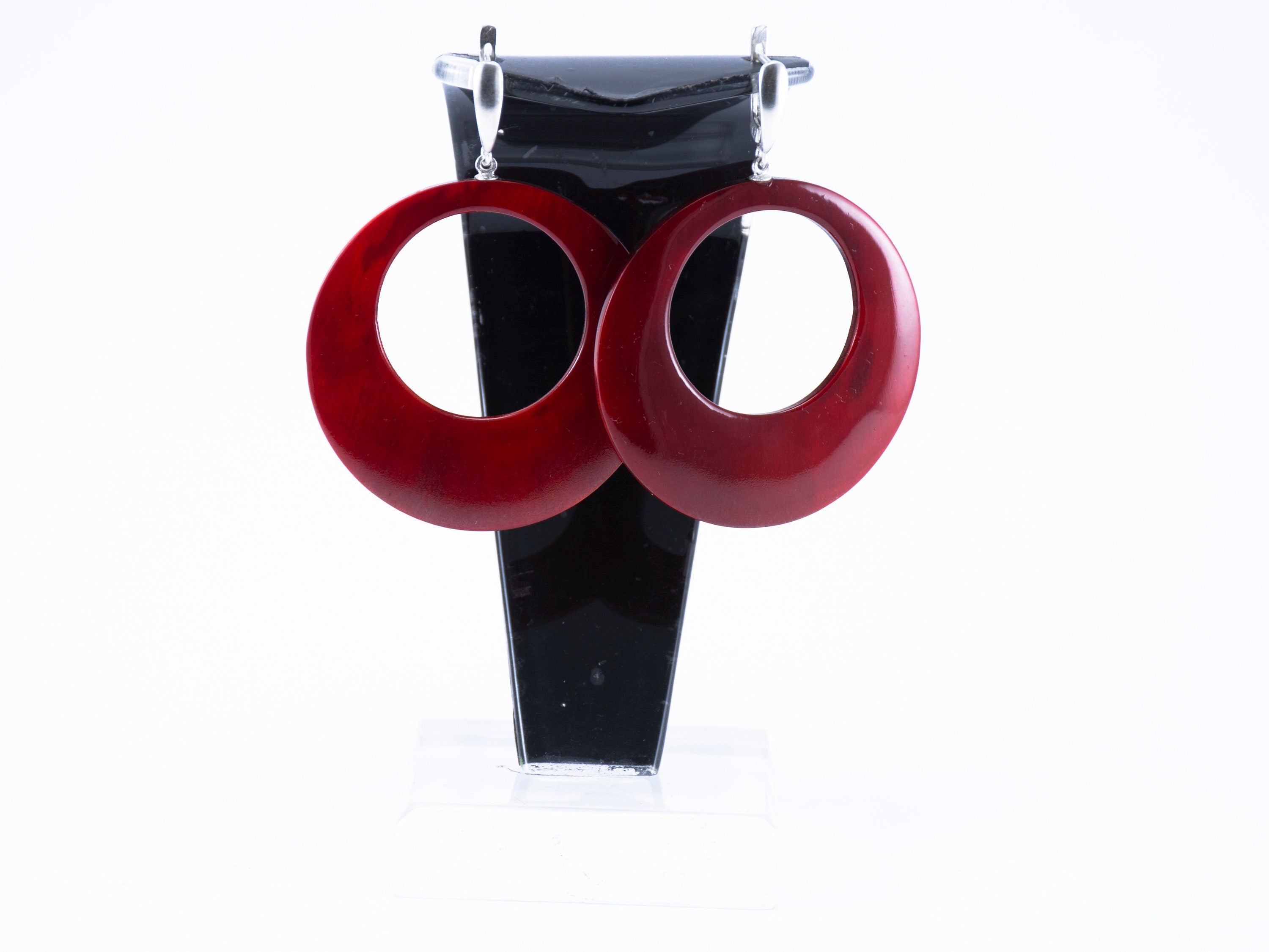 Stylish hand-carved buffalo horn earrings in red color with silver locks, showcasing intricate craftsmanship and unique design.