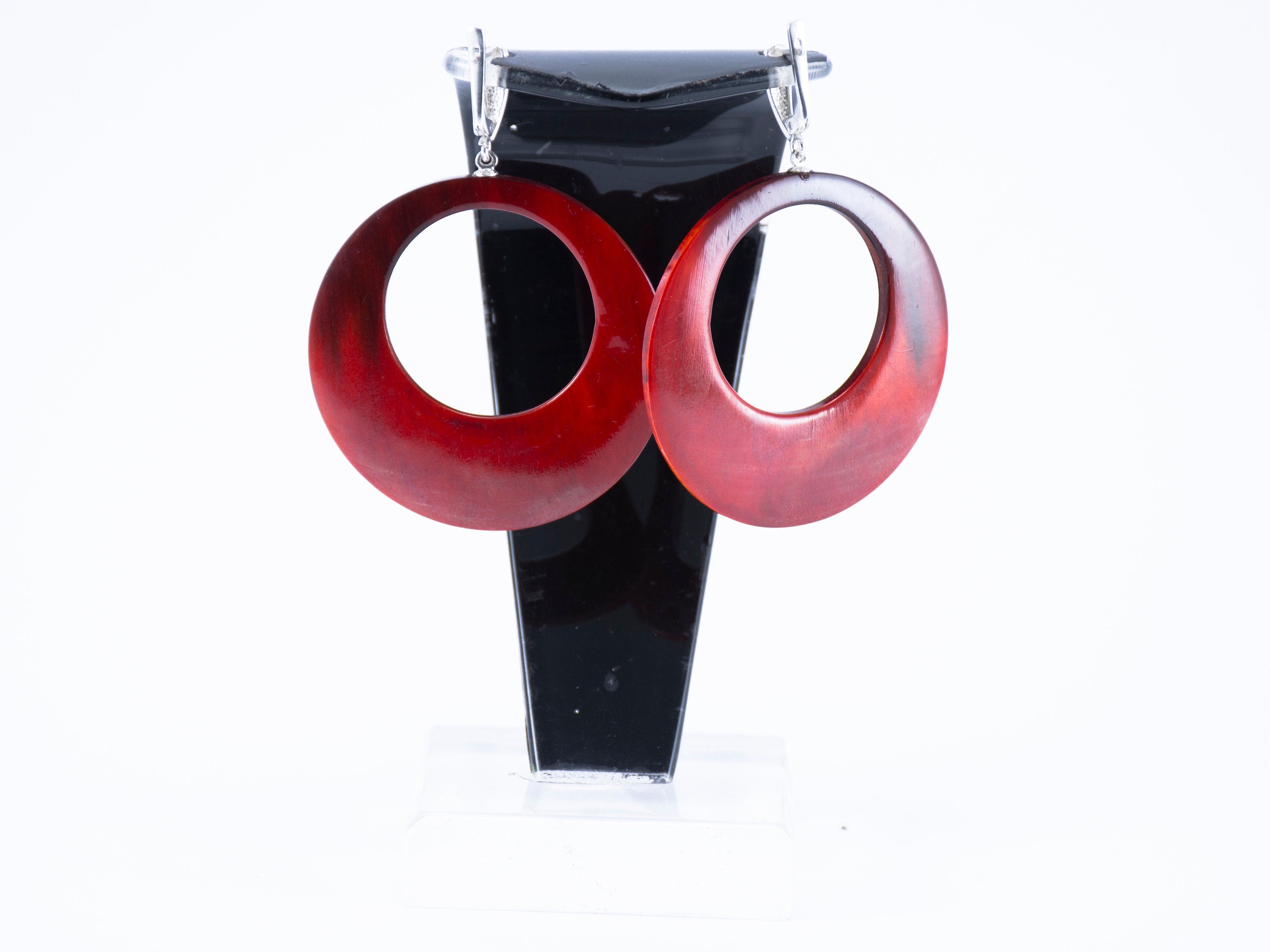 Stylish hand-carved buffalo horn earrings in red color with silver locks, showcasing intricate craftsmanship and unique design.