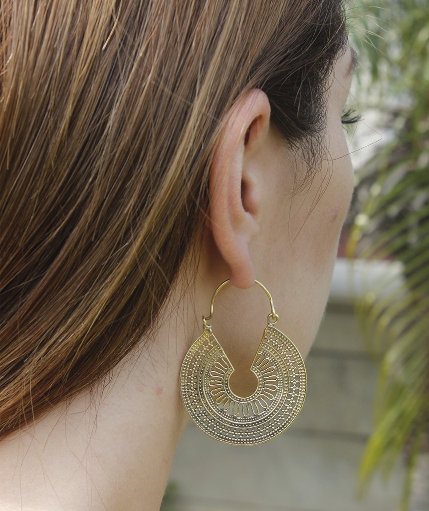 A pair of ornate brass hoop earrings with intricate etched designs, showcasing their unique craftsmanship and elegant finish.