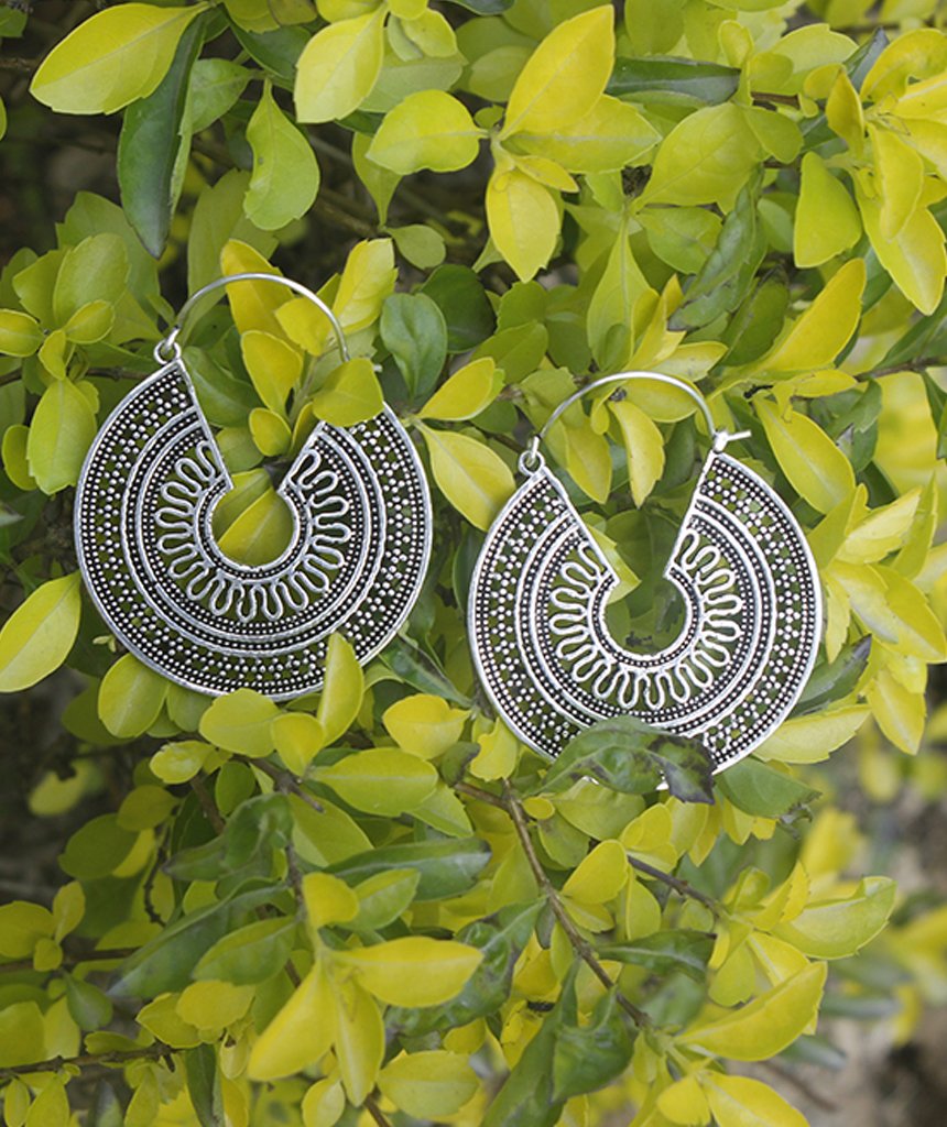 A pair of ornate brass hoop earrings with intricate etched designs, showcasing their unique craftsmanship and elegant finish.