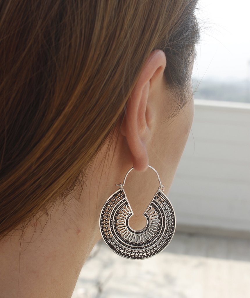 A pair of ornate brass hoop earrings with intricate etched designs, showcasing their unique craftsmanship and elegant finish.