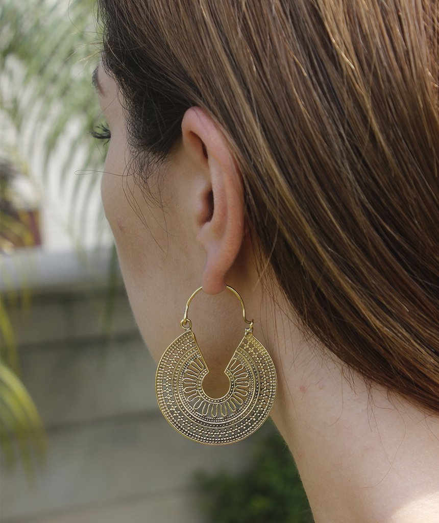 A pair of ornate brass hoop earrings with intricate etched designs, showcasing their unique craftsmanship and elegant finish.