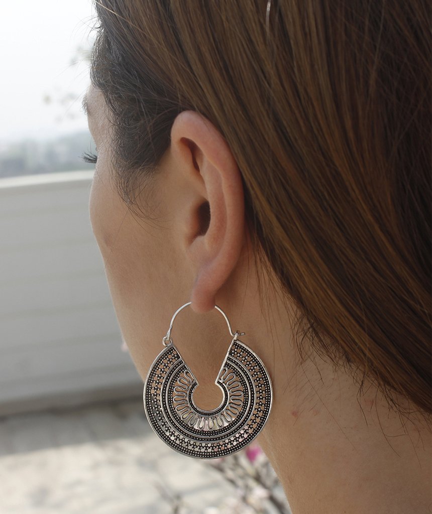 A pair of ornate brass hoop earrings with intricate etched designs, showcasing their unique craftsmanship and elegant finish.