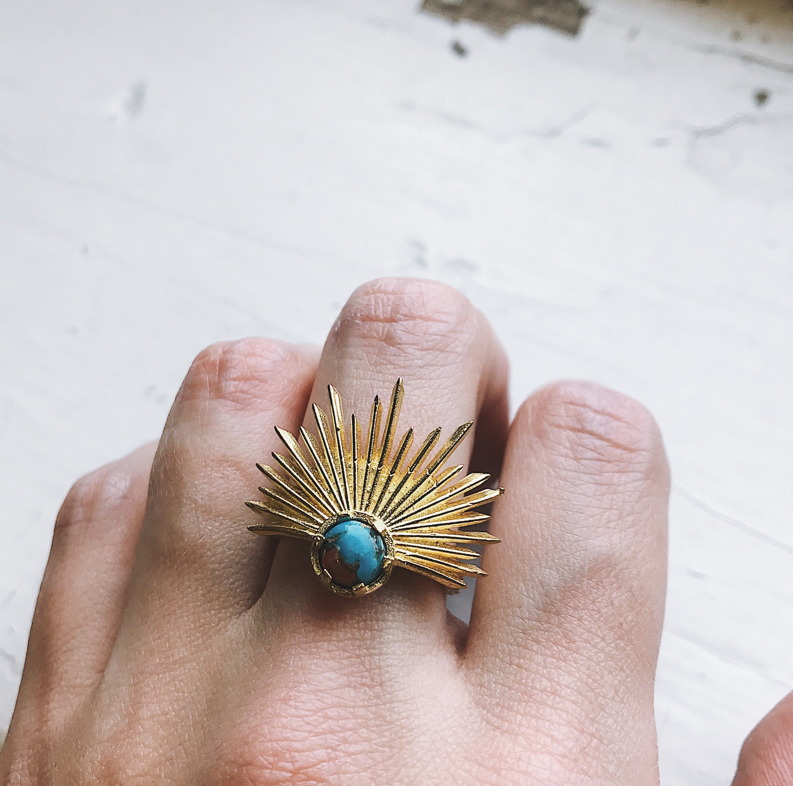 A stunning Sun Goddess Ring featuring a vibrant copper oyster turquoise stone set in a gold-tone sunburst design, showcasing its unique craftsmanship.