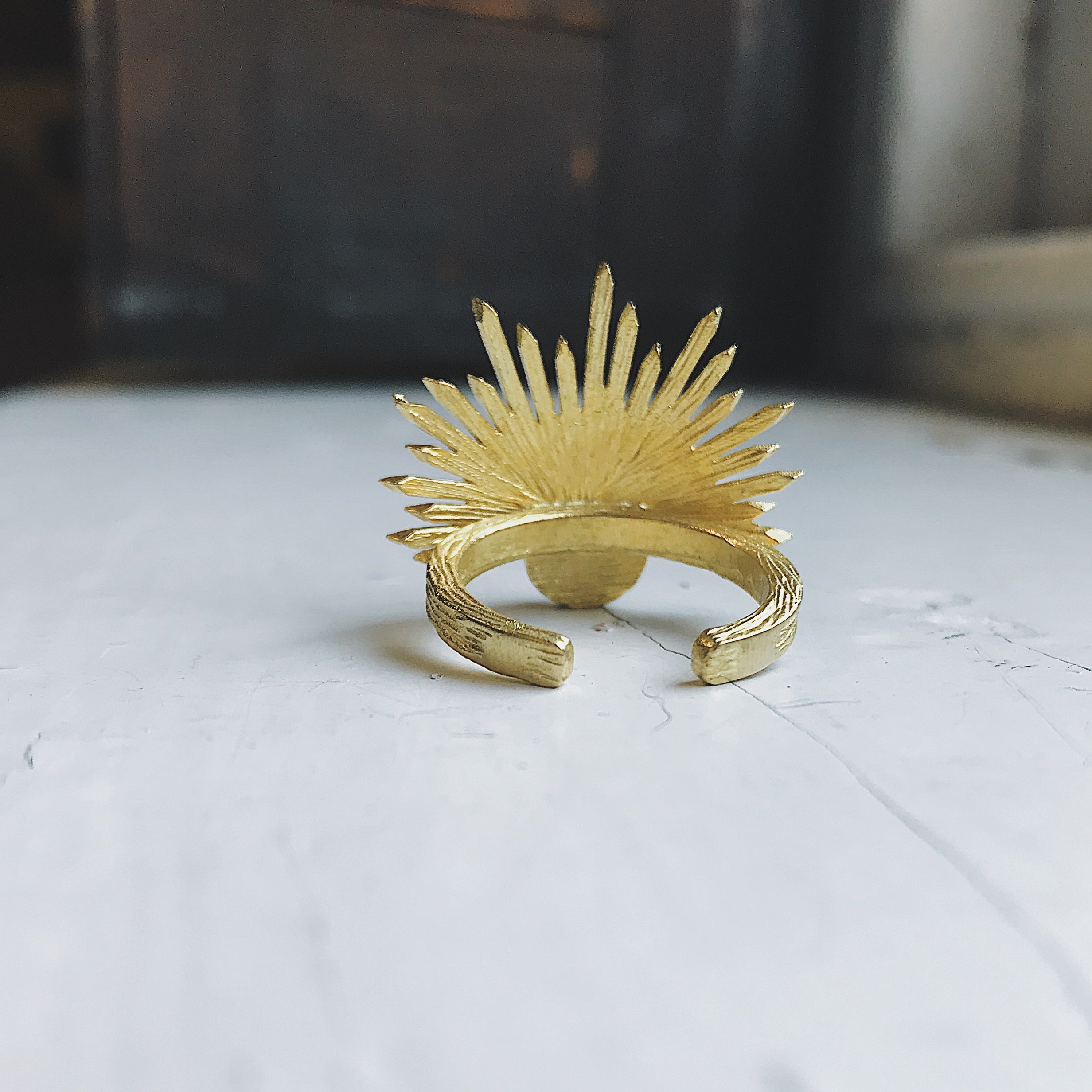 A stunning Sun Goddess Ring featuring a vibrant copper oyster turquoise stone set in a gold-tone sunburst design, showcasing its unique craftsmanship.