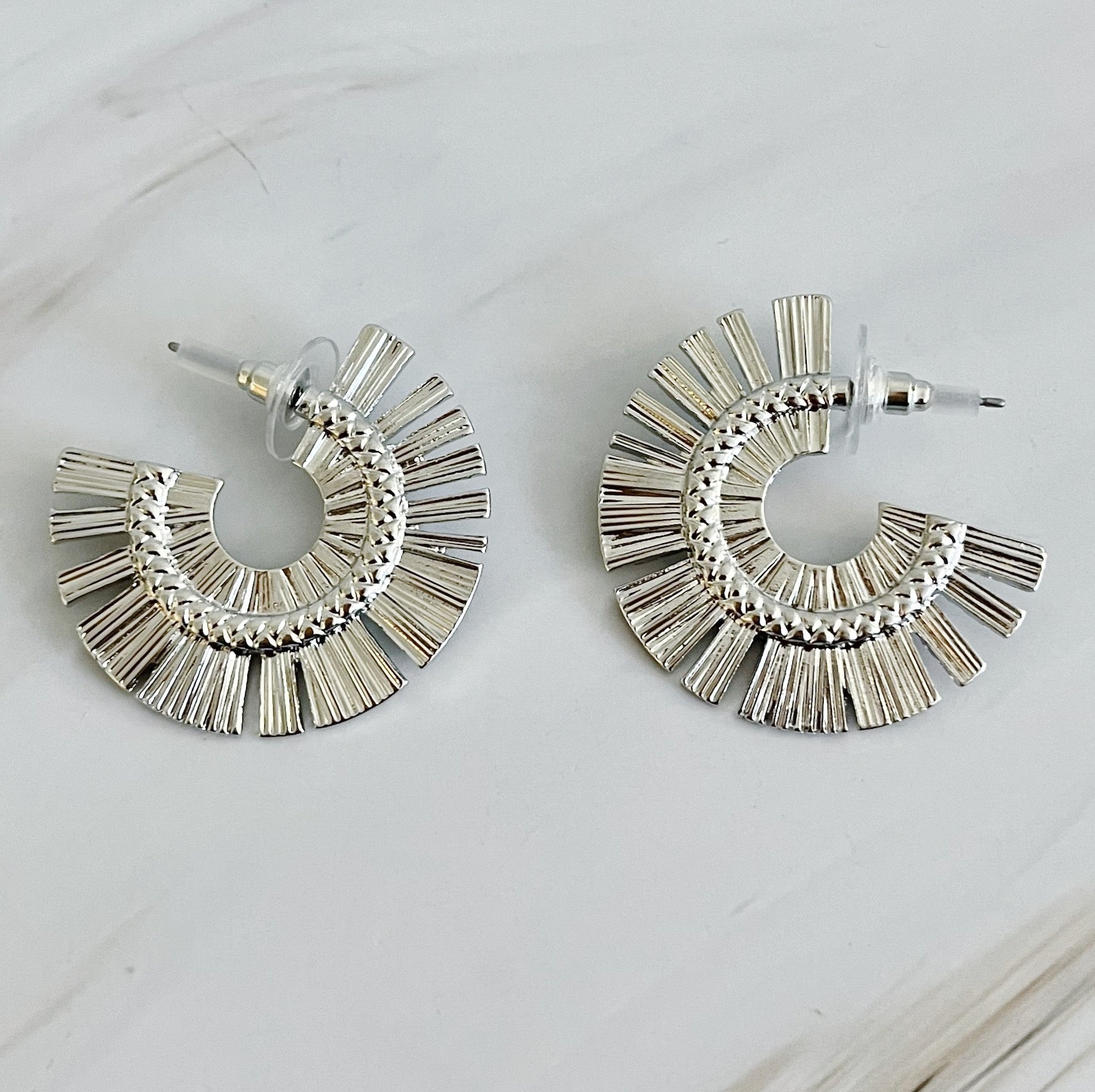 A pair of Sunburst Beauty Hoop Earrings featuring a unique sunburst design, made from plated alloy metal with a 1-inch diameter.