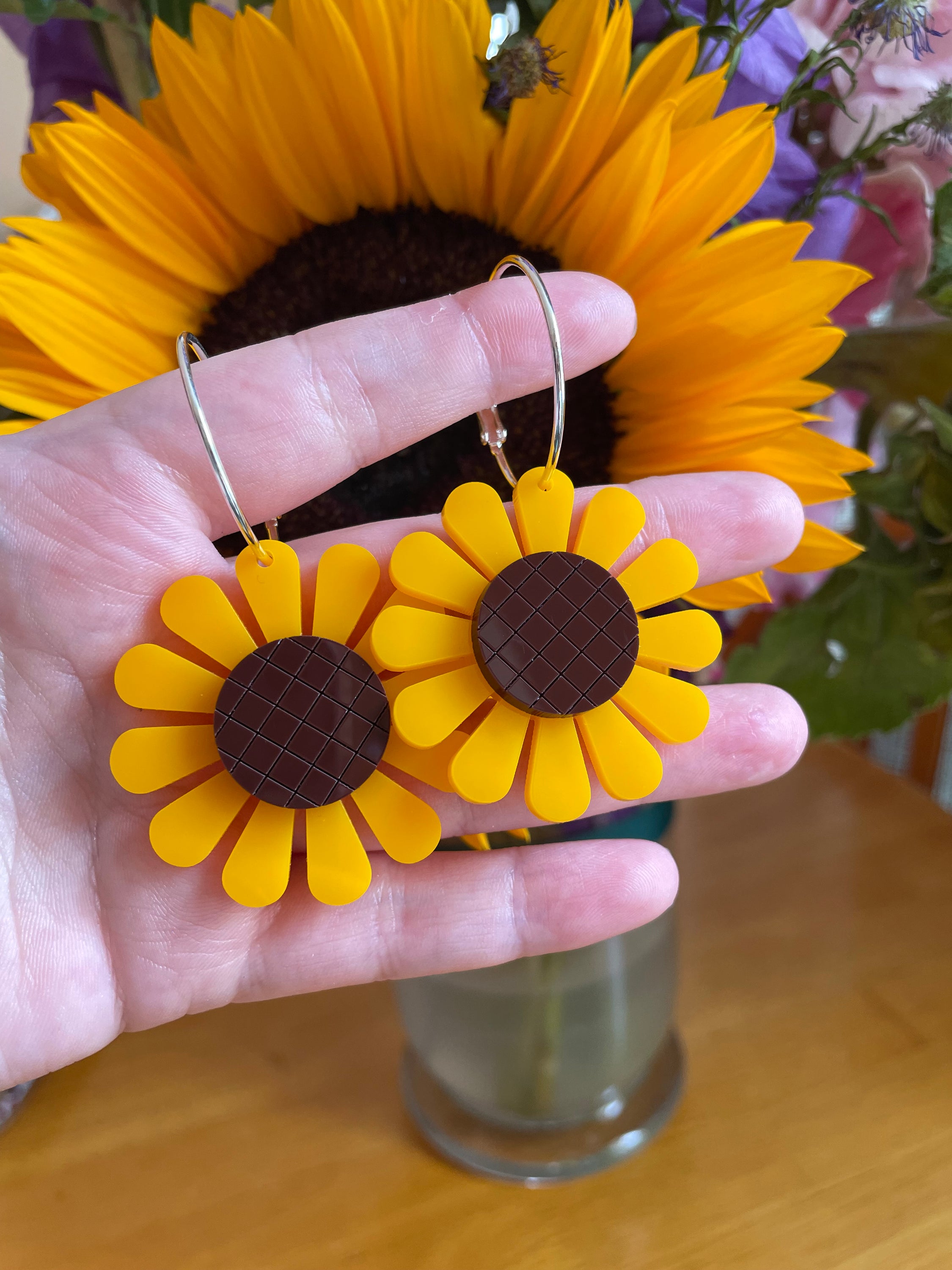 A pair of vibrant sunflower hoop earrings made from laser-cut acrylic, showcasing a unique floral design with a vintage touch.